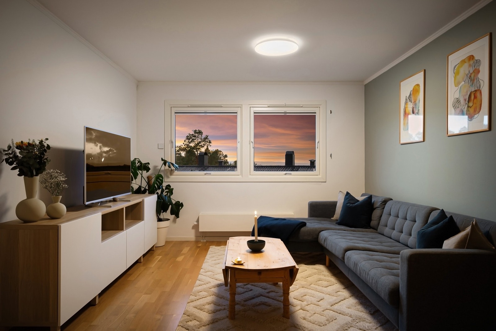 Sofaen har sin naturlige plassering i enden av stuen og det er godt med naturlig lys inn fra begge sider Galleribilde