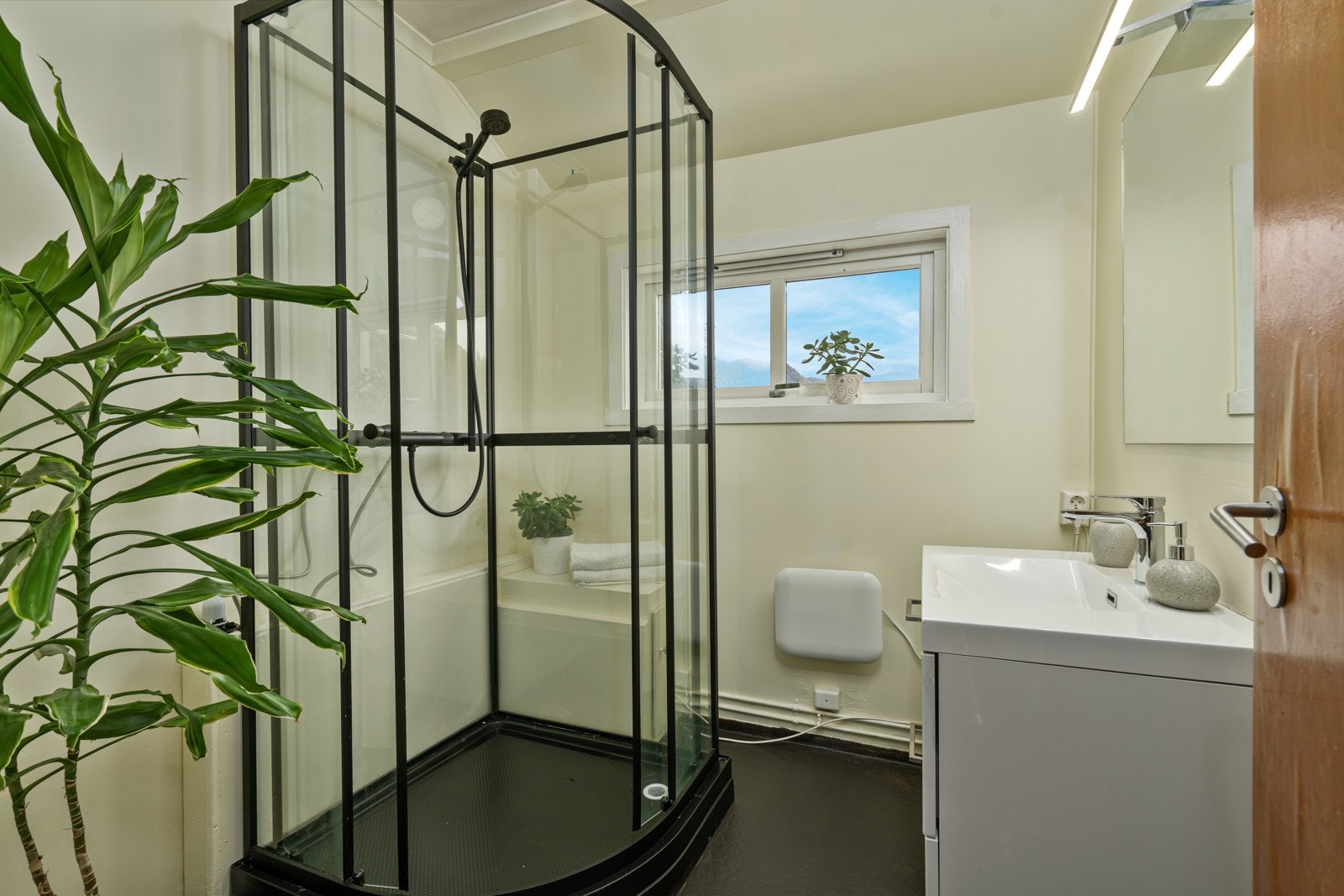 Badet har vinylbelegg på gulv med oppbrett langs vegger, malte plater på vegger og i himling. Rommet er innredet med dusjkabinett samt servantinnredning med nedfelt servant. Baderomsmøblene er fra 2023. Galleribilde