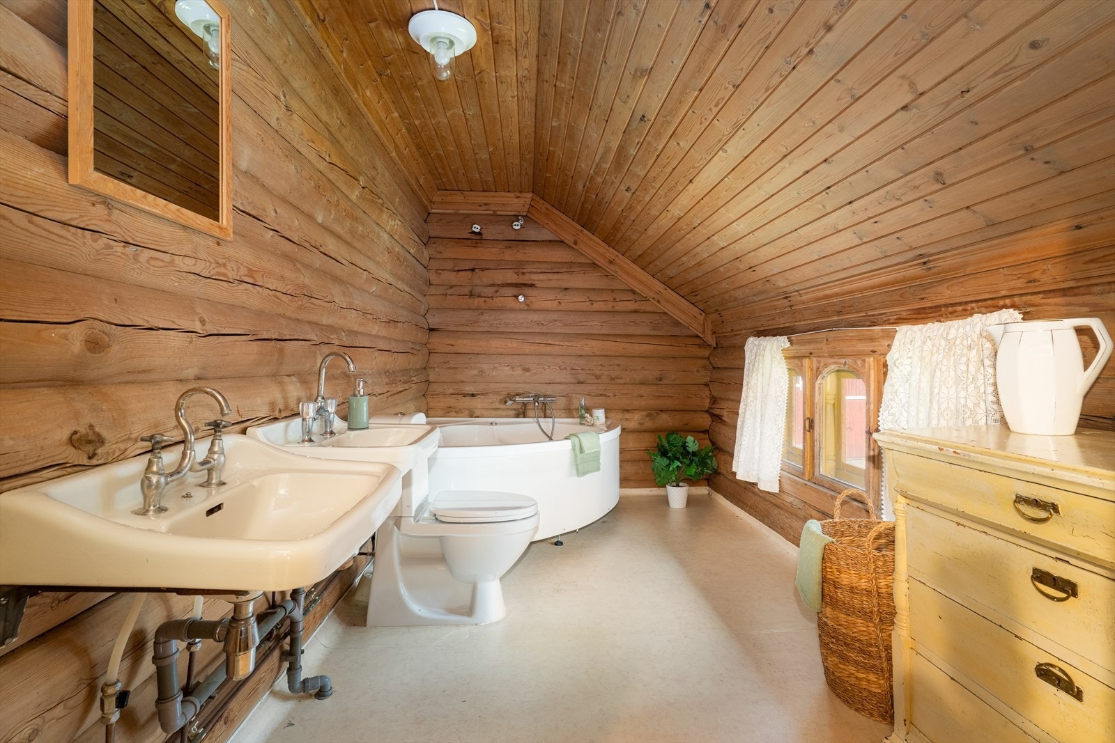 Badet inneholder toalett, to servanter og hjørnebadekar. Galleribilde