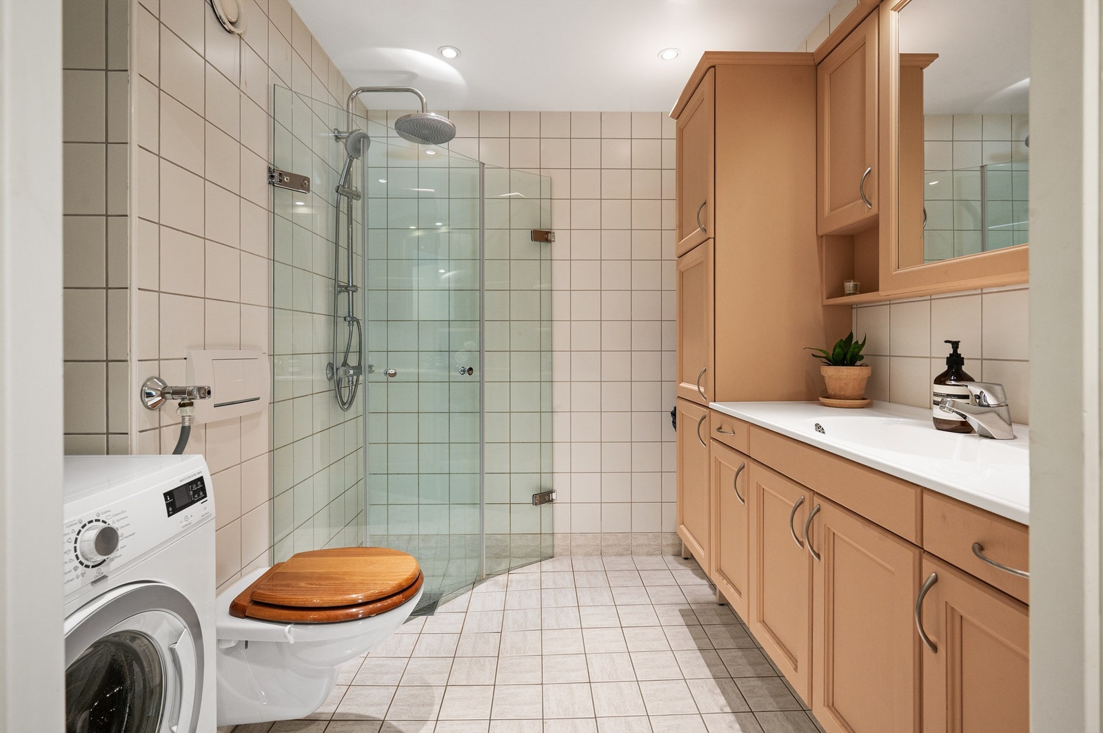 God størrelse på baderommet med innfellbare glassdører, regnfallsdusj, varmekabler i gulv og rom for mye oppbevaring. Opplegg for vaskemaskin. Galleribilde