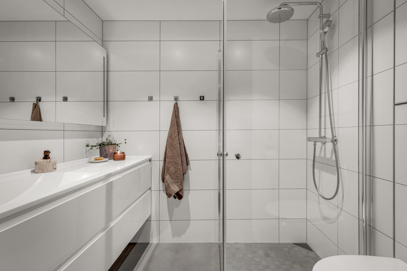 Leiligheten har to bad. Begge badene har fliser på gulv og vegger, dusj, vegghengt toalett og servant med skuffeseksjon. Galleribilde