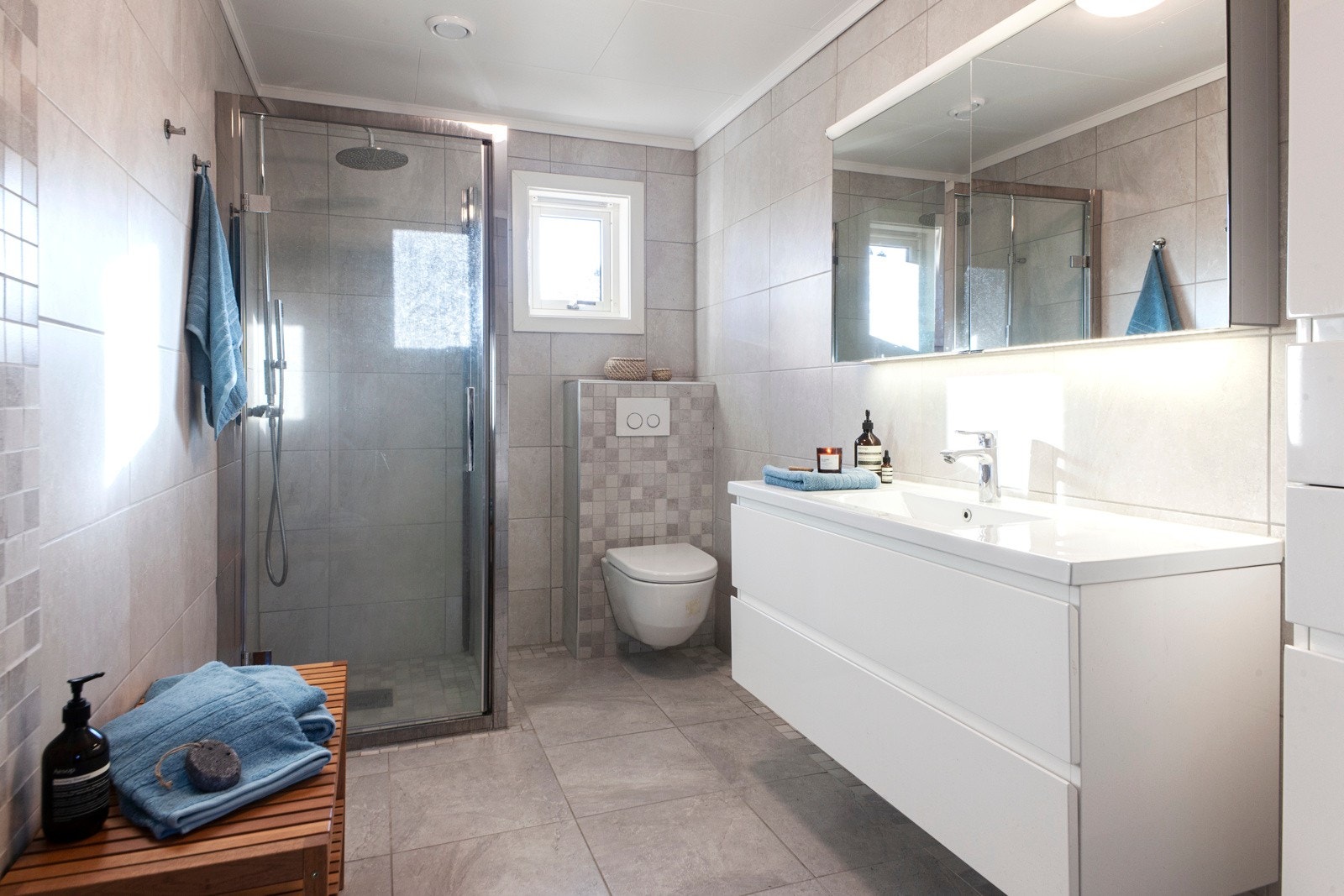 Boligen har to bad og et vaskerom. Dette badet ble pusset opp i 2013 og har delikate fliser og dusjhjørne med regndusj. Galleribilde