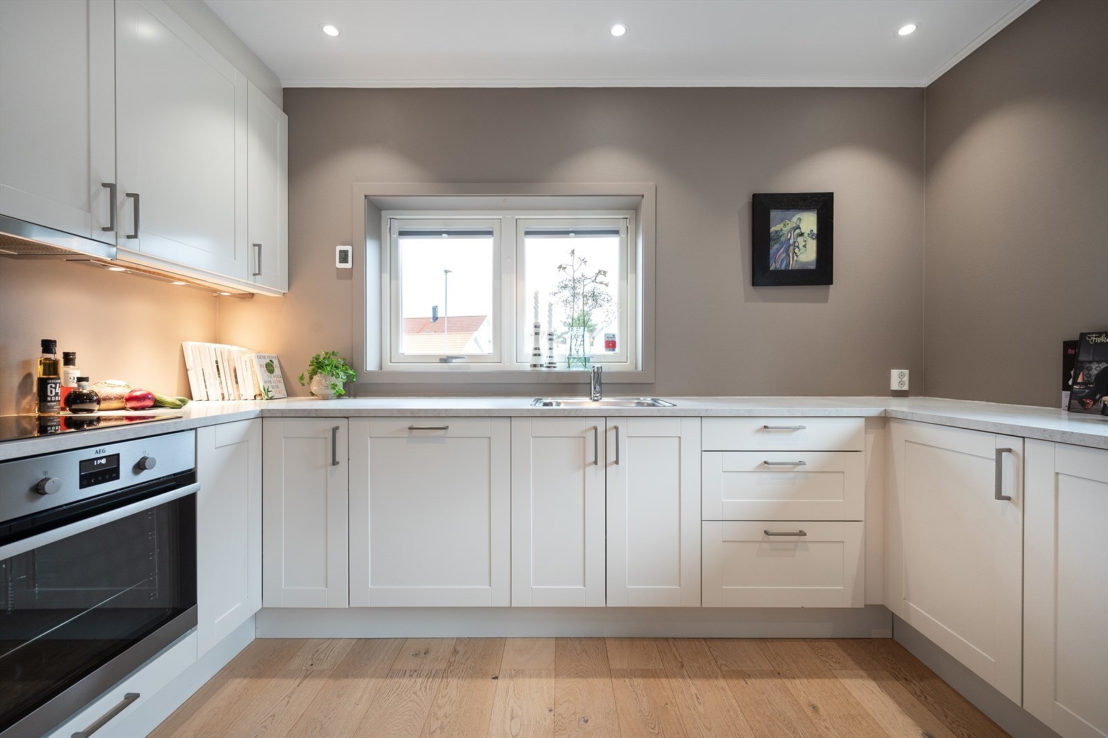 Kjøkkeninnredningen fra Sigdal fyller tre vegger, med hvite enkle fyllingsprofiler, og rommet får godt med lys fra to kanter. Galleribilde