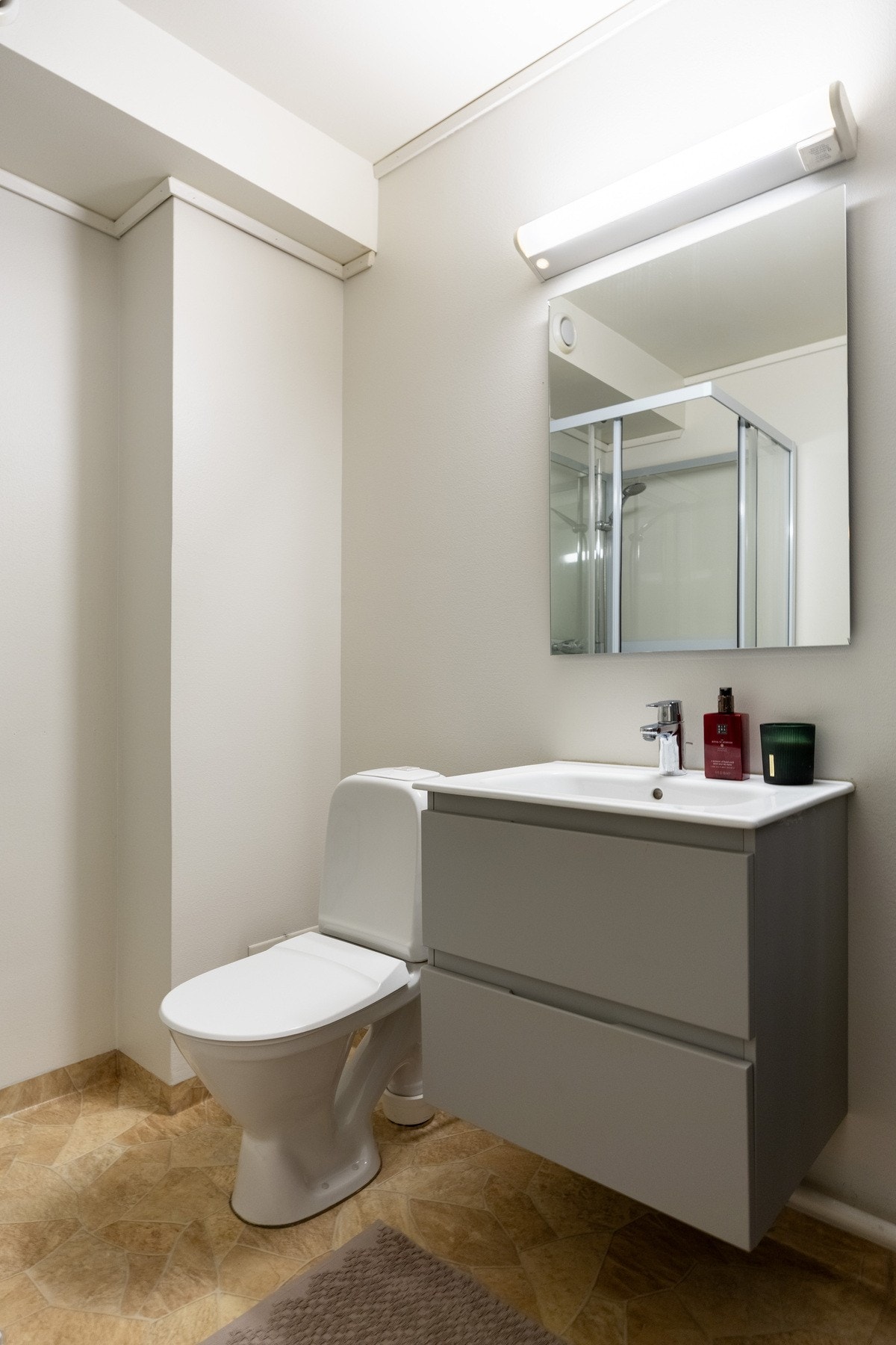 Badet er innredet med servantskap med ovenpåliggende servant og ett-greps armatur, speil, belysning og stikkontakt over servant, gulvstående toalett, samt dusjkabinett. Galleribilde