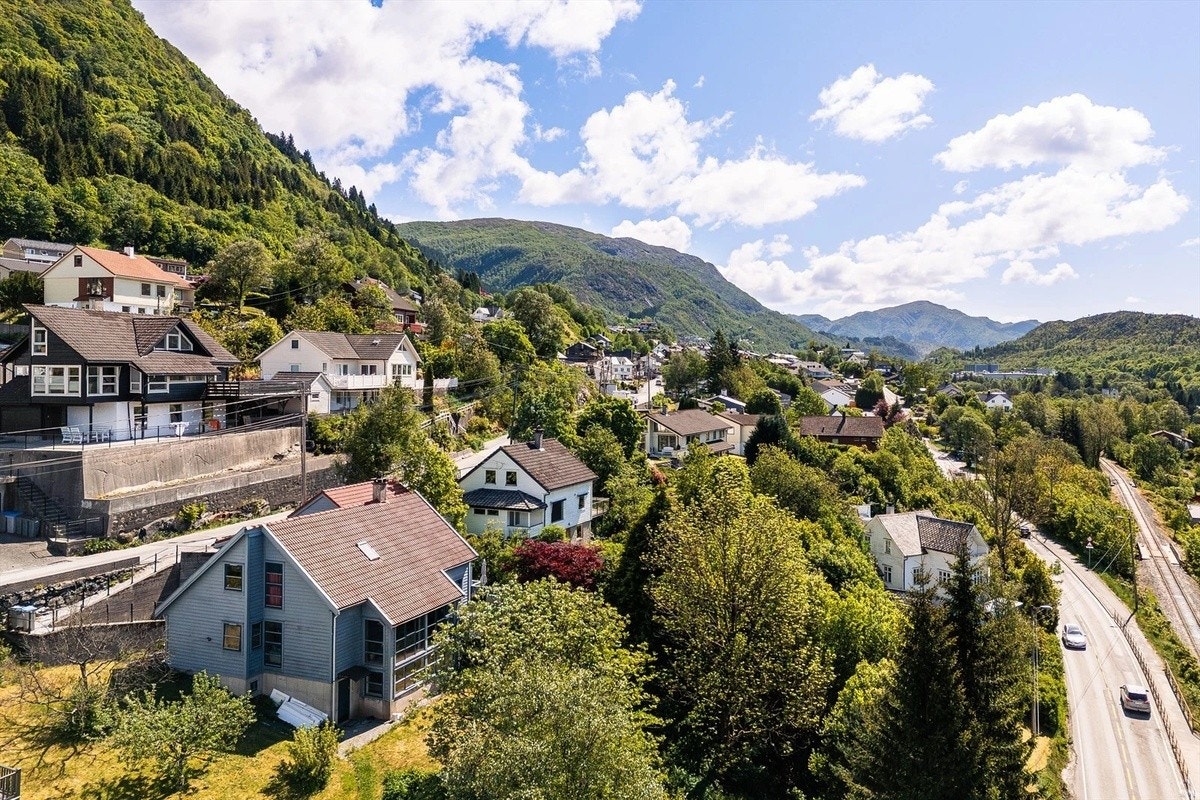 Blått hus nede til venstre på bildet. Arkitekttegnet enebolig. Garasje i bakkant av bygget, bod med lagringsplass. Kollektivet går over husets 1. og 2. etasje. Galleribilde