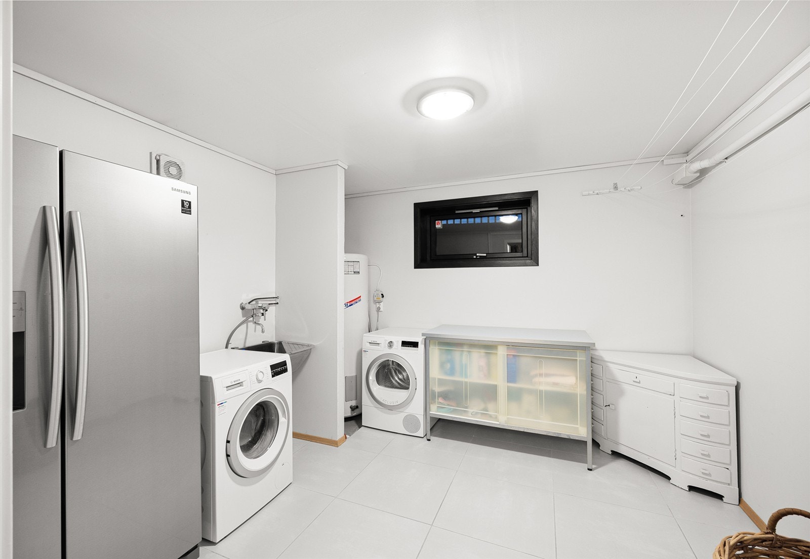 Praktisk vaskerom med varmekabler i gulv. Her er det installert varmtvannsbereder og sentralstøvsuger, samt vannledninger med hovedstoppekran og vannmåler. Galleribilde