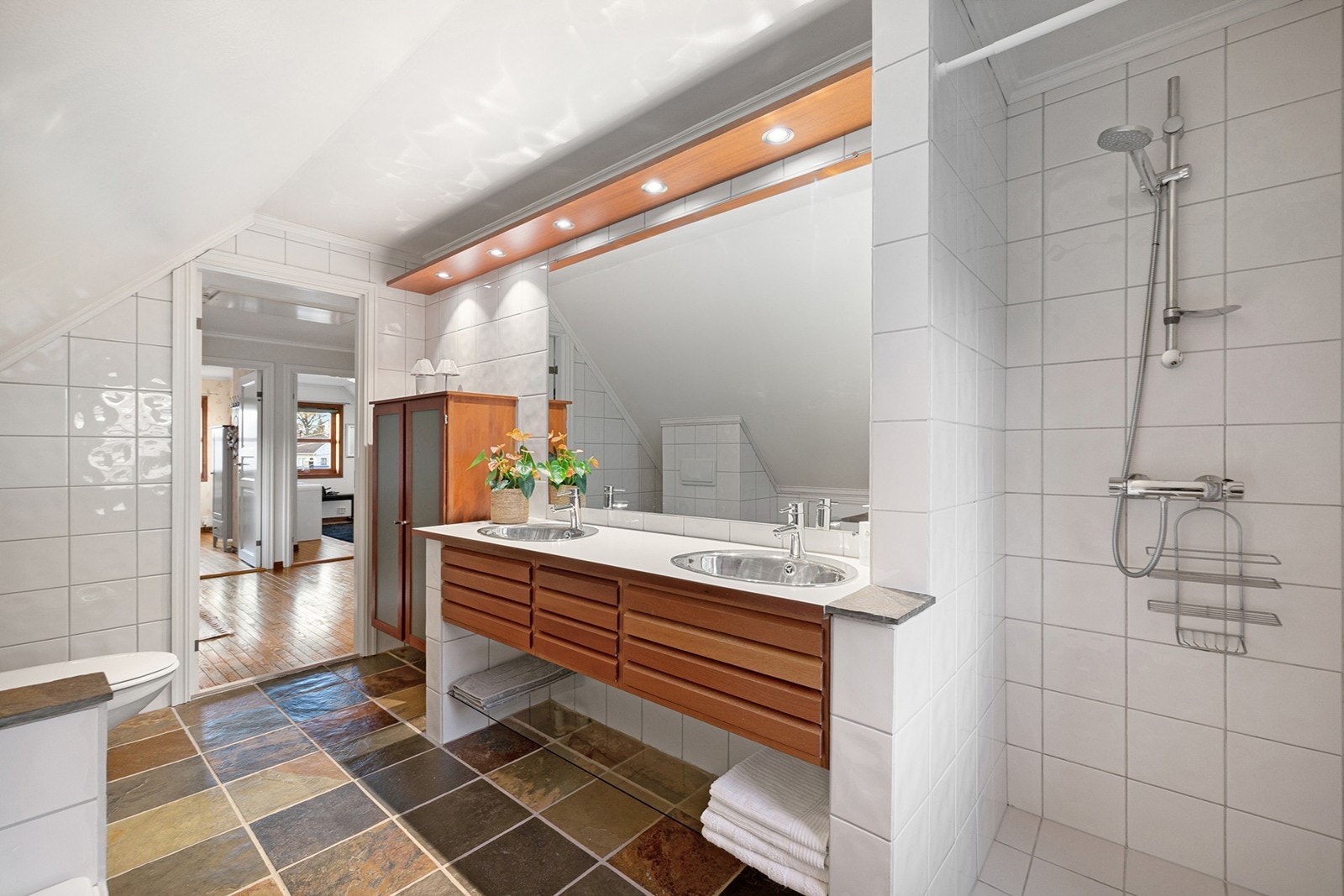 Lyst og romslig bad med flislagt gulv i naturstein og elektriske varmekabler. Galleribilde