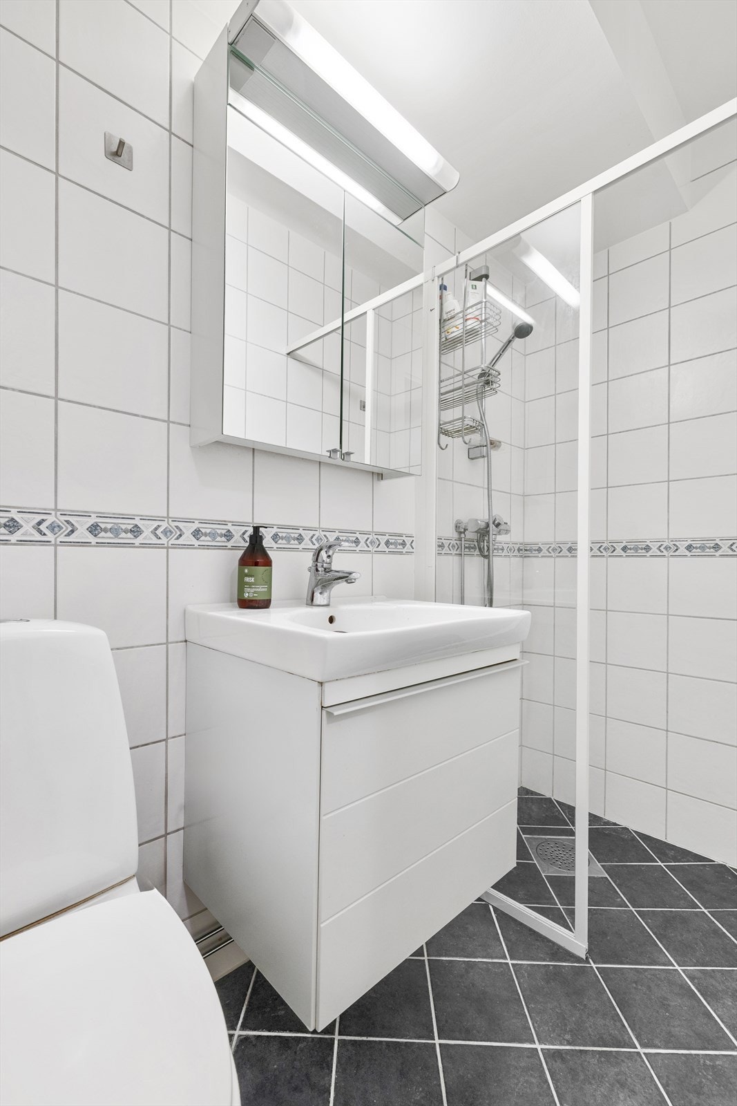 Badet er innredet med gulvstående toalett, servantinnredning med servant og varmekabler i gulv Galleribilde