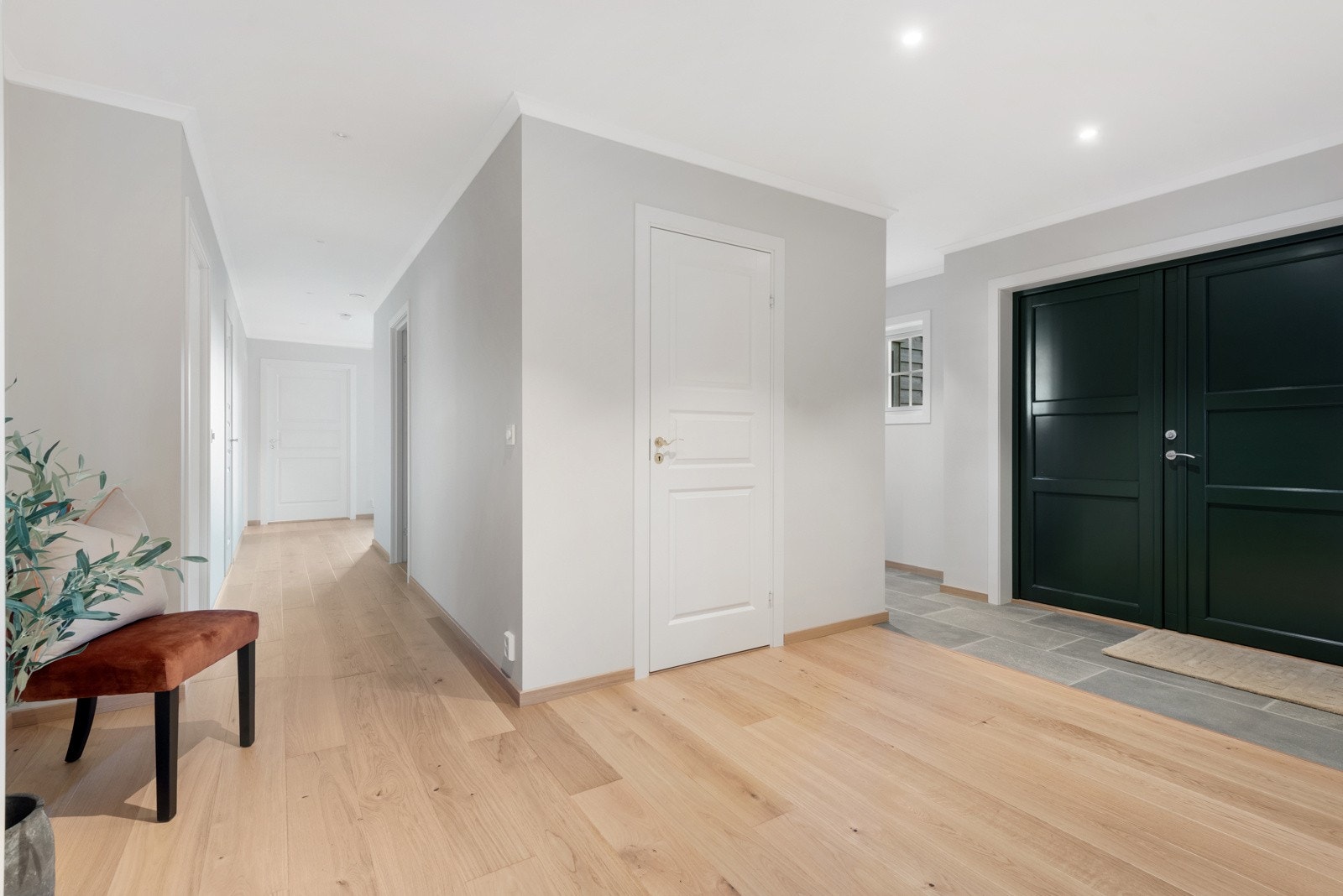 Du kommer i en romslig entré med fliser på gulvet og adkomst til garderobe og gjestetoalett Galleribilde