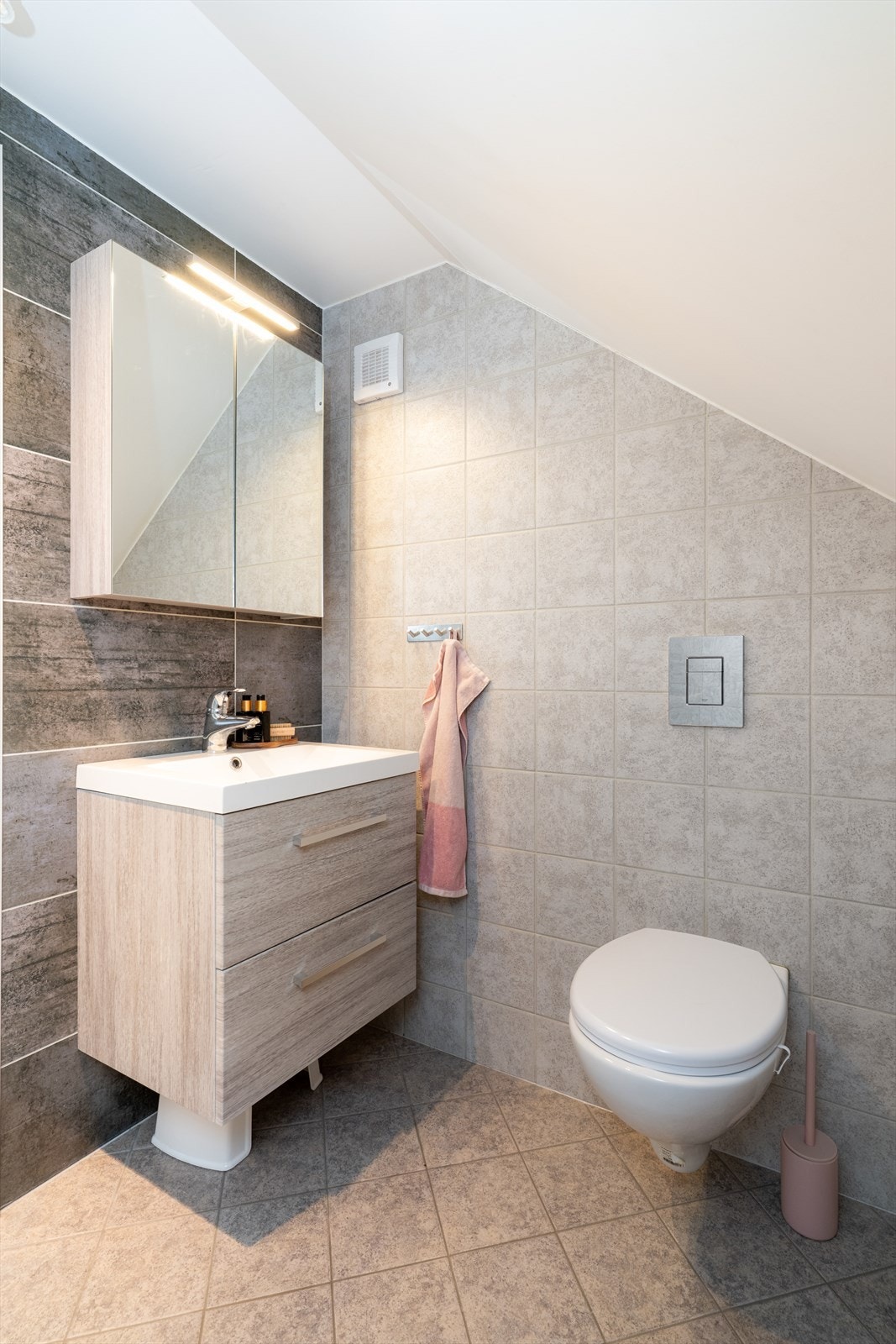 Også her er det varmekabler i gulvet, samt innredning med dype skuffer og heldekkende servant. Speilskap med ytterligere oppbevaringsplass og overlys. Galleribilde