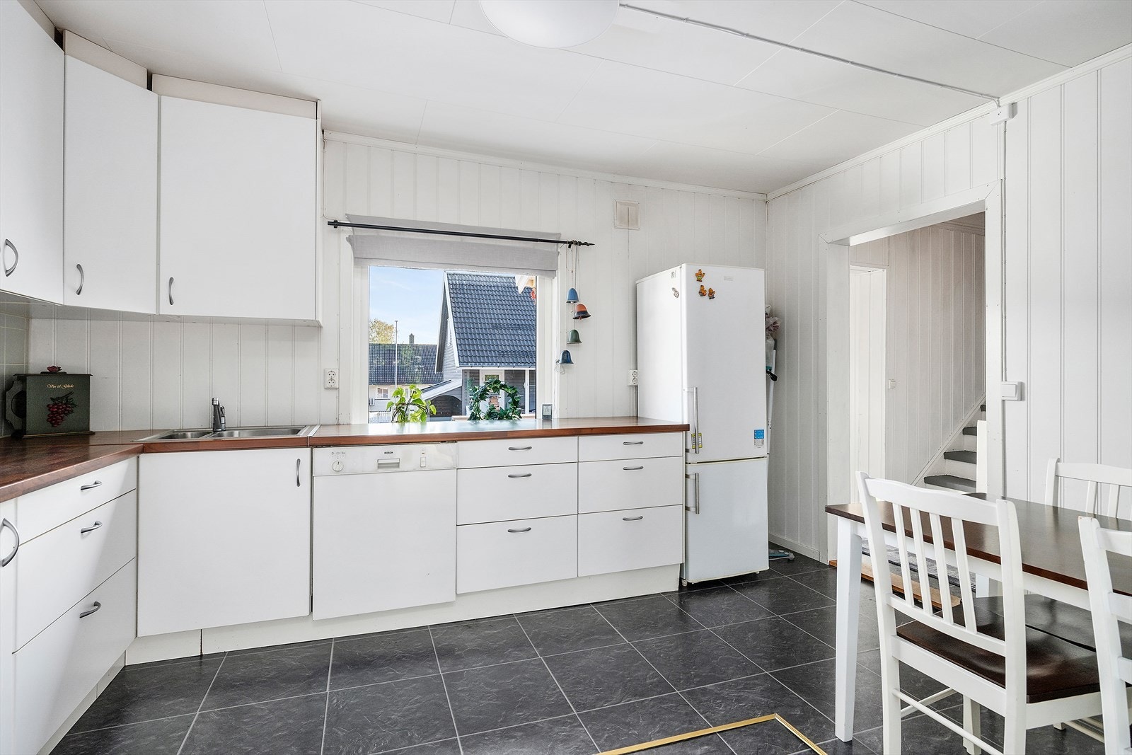 Lyst og funksjonelt kjøkken med hvite fronter, benkeplate i tre og spiseplass. En hyggelig sone for både matlaging og hverdagsmåltider. Galleribilde