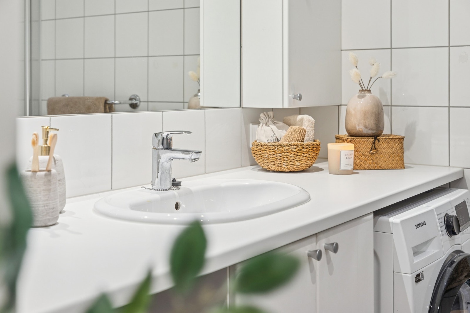 Innbydende baderom med vegghengt servantinnredning, dushjørne med dører og opplegg for vaskemaskin. Galleribilde