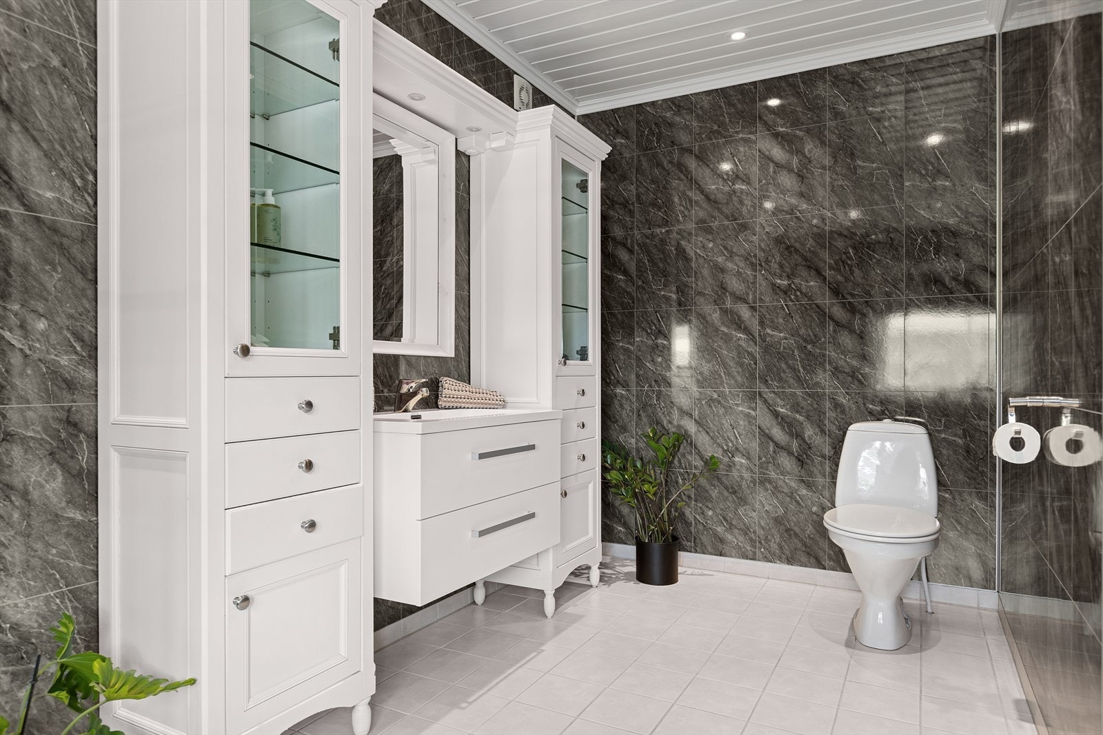 Boligens bad har fliser på gulv og baderomsplater på veggene. Galleribilde