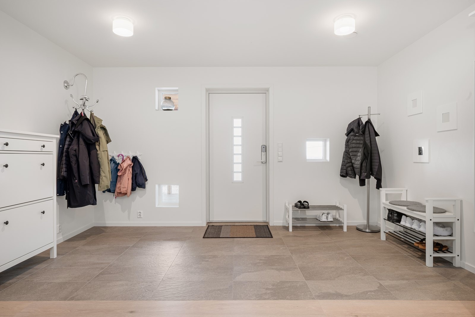Du kommer inn i en romslig gang/hall med god plass for oppbevaringsløsninger til yttertøy og sko. Det er flislagt gulv med gulvvarme innenfor ytterdøra. Galleribilde
