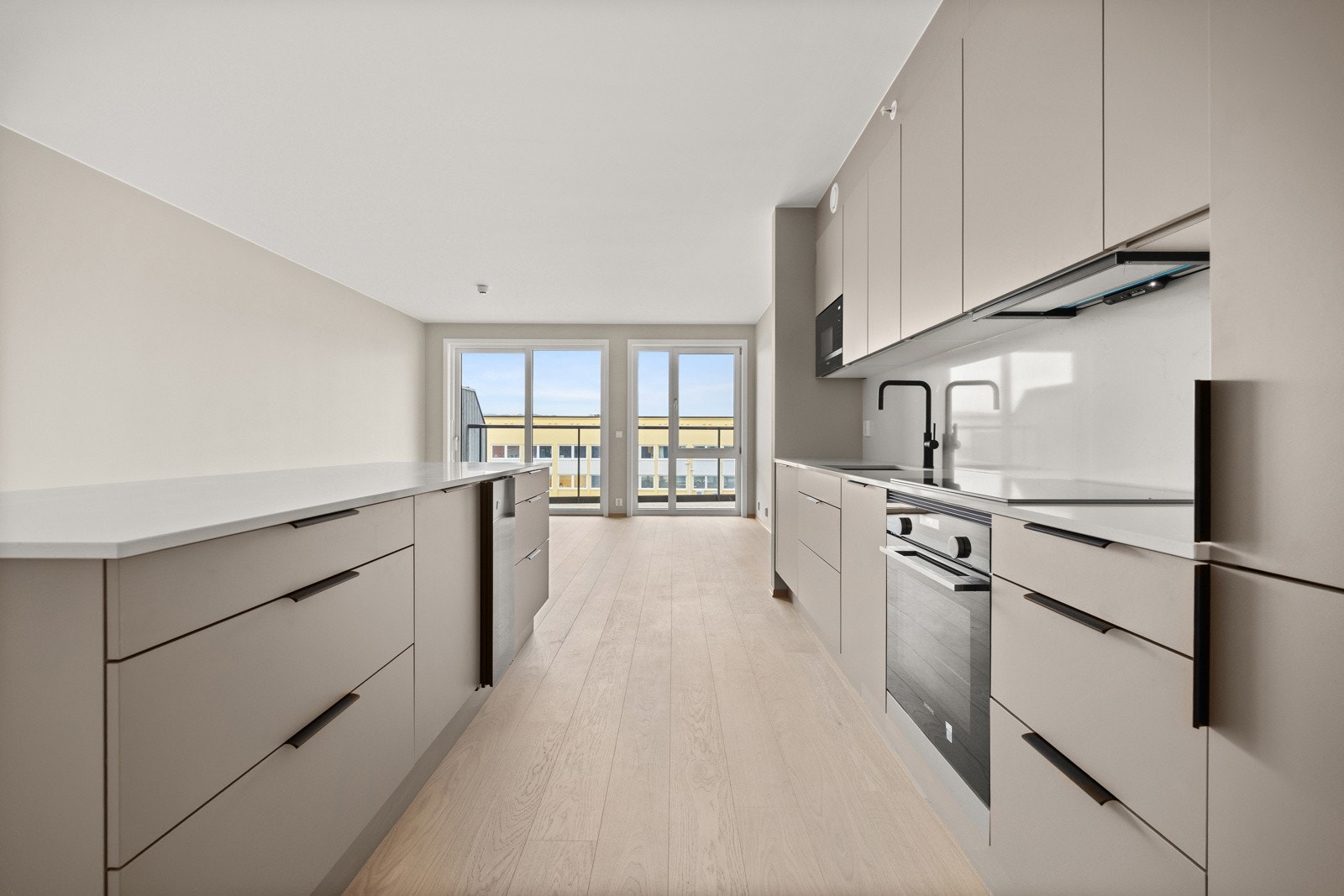 Beige, glatt innredning med minimalistisk design og helintegrerte hvitevarer. Galleribilde