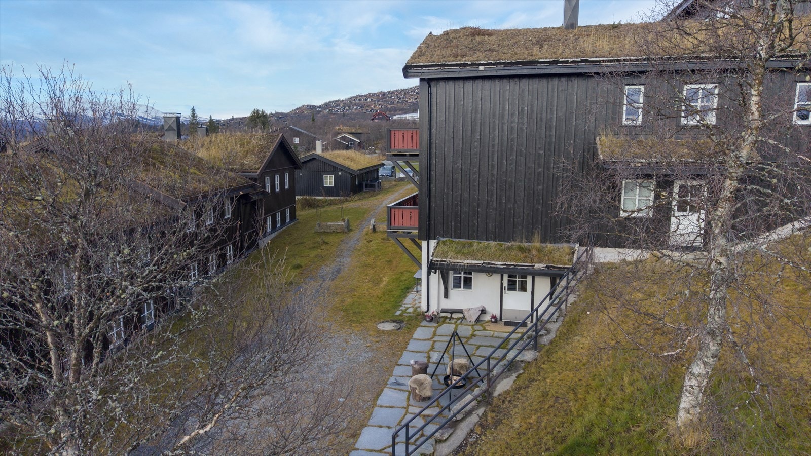 Leiligheten ligger i førsteetasje, sentralt og likevel skjermet med brøytet vei til døra, slik at man kan sette av bagasje og parkere bilen i garasje, eller hvis el-bil, sette den til lading. Galleribilde