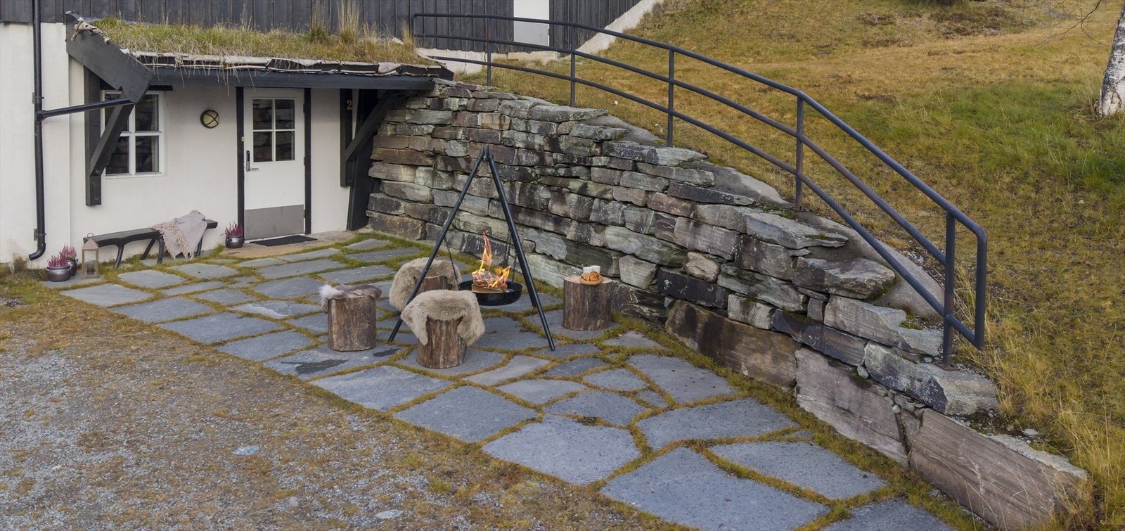 Overbygd inngangsparti med 20 kvm. skiferlagt uteplass -stylet med bålpanne for anledningen, men egnet for solide utemøbler og solrik avslapning fra morgen til kveld. Galleribilde