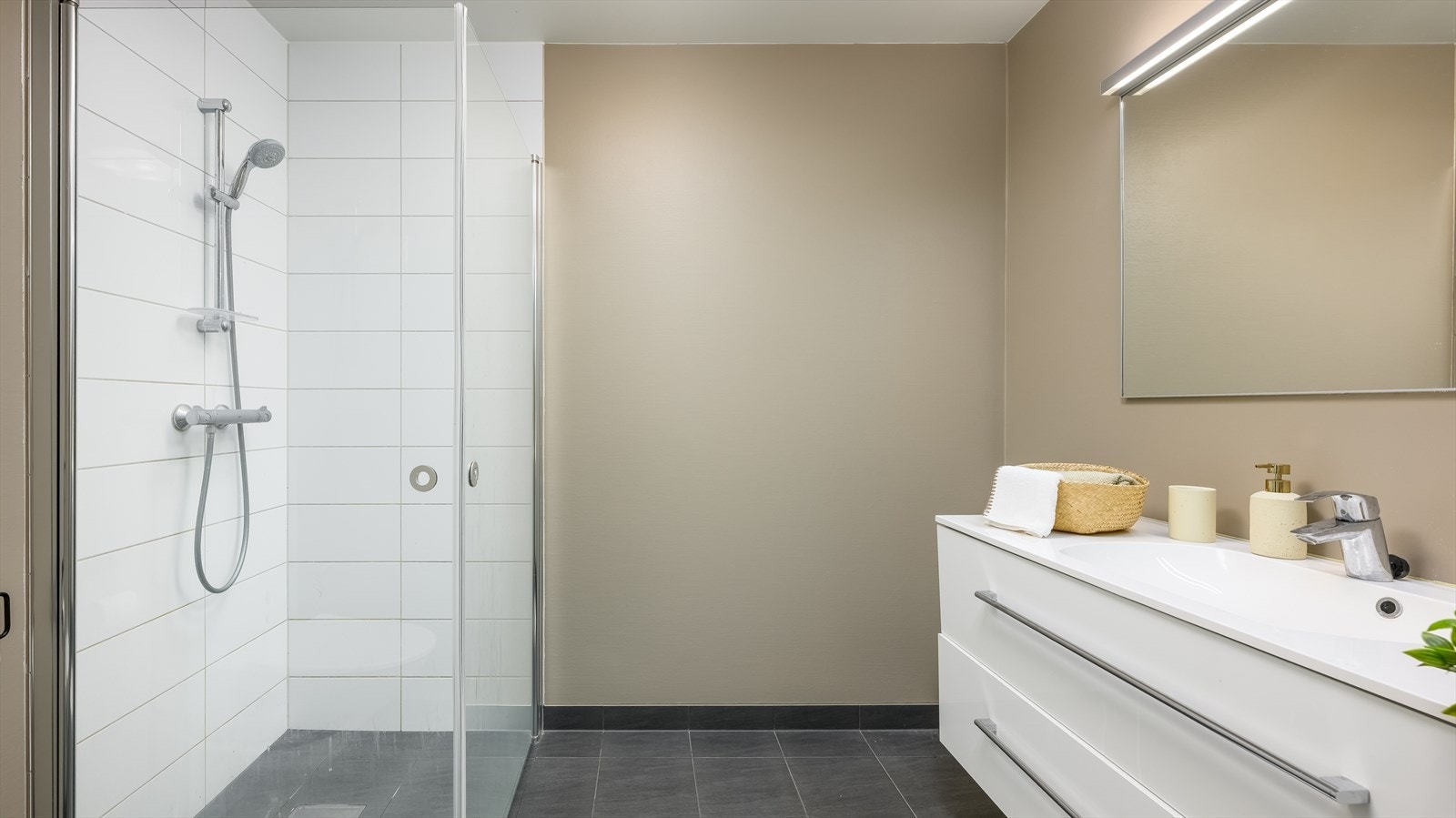 På badet er det vegghengt toalett og et dusjhjørne med innfellbare glassdører. Galleribilde