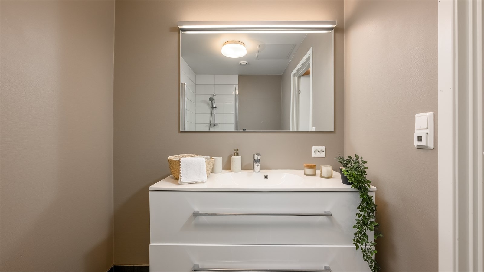 På badet er det vegghengt toalett og et dusjhjørne med innfellbare glassdører. Galleribilde