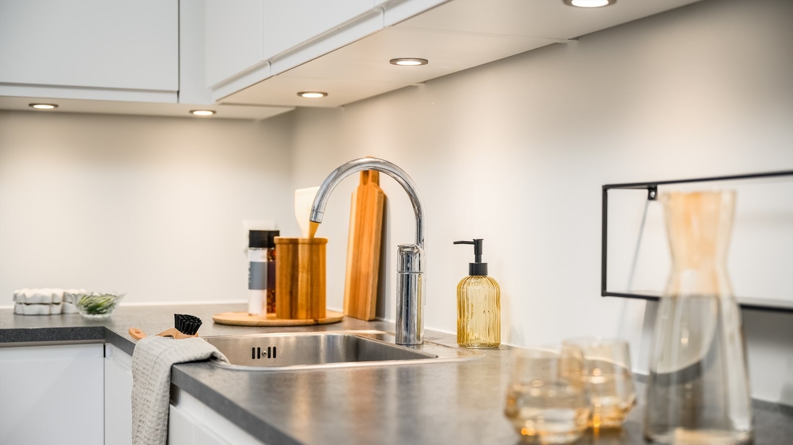 Spotter er montert over benken, og over kokesonen har kjøkkenet en komfyrvakt og en ventilator. Integrert i innredningen finner man stekeovn, oppvaskmaskin og induksjonstopp. Galleribilde