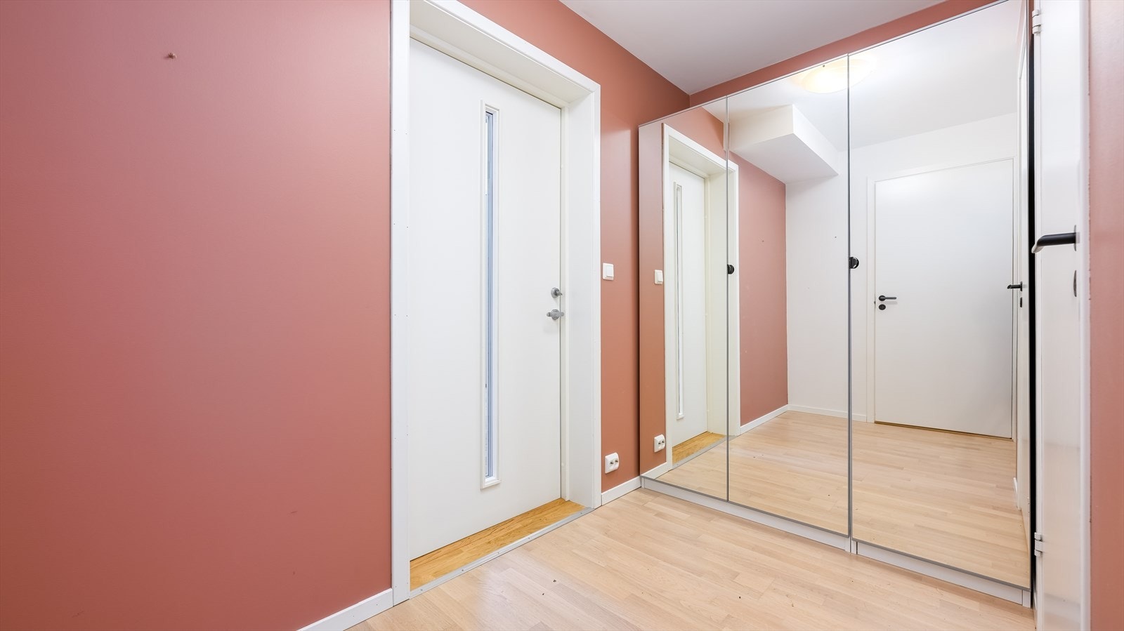 Entreen ligger direkte tilknyttet stuen, med det samme lyse parkettgulvet. Langs den ene veggen står det et stort garderobeskap med speilfronter for ekstra romfølelse. Galleribilde