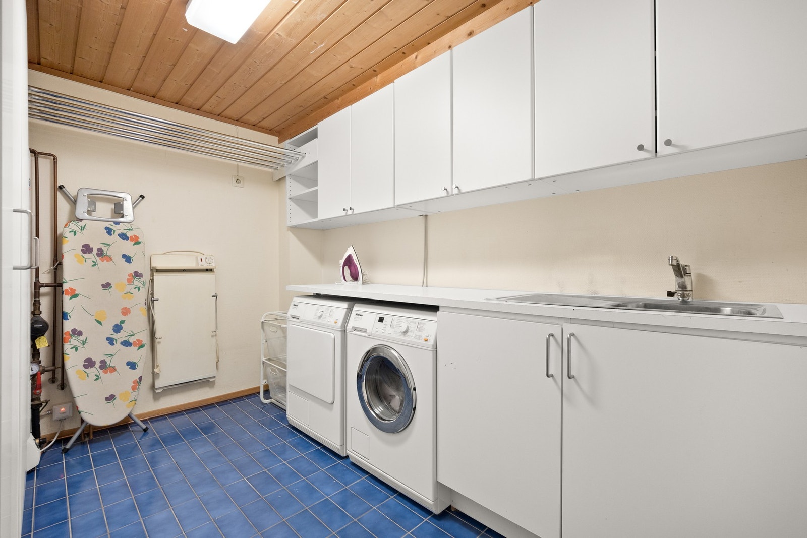 Vaskerom har fliser på gulvet og malte vegger. Det er opplegg til vaskemaskin og skylle kum. Vaskerommet er fra byggeåret. Galleribilde