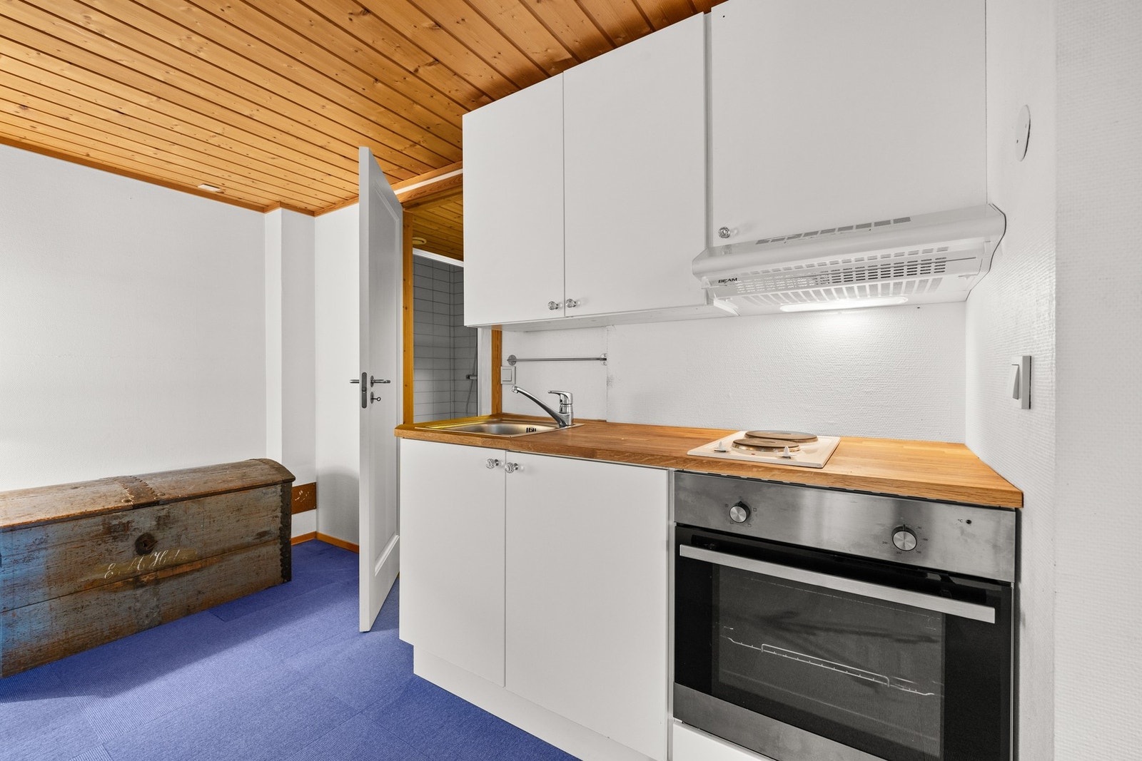 Hvit kjøkkeninnredning med slette fronter og heltre benkeplate Det er integrert koketopp og stekeovn Galleribilde