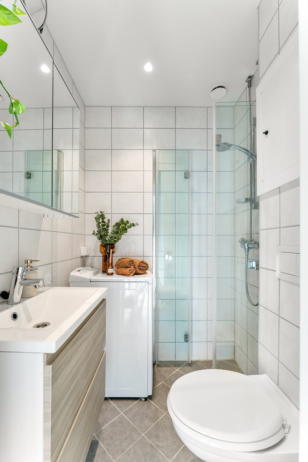 Bad rehabilitert i regi borettslaget 2019. Badet har dusj med glassdører, opplegg for vaskemaskin, veggmontert toalett, servant med skuffer og speilskap. Galleribilde