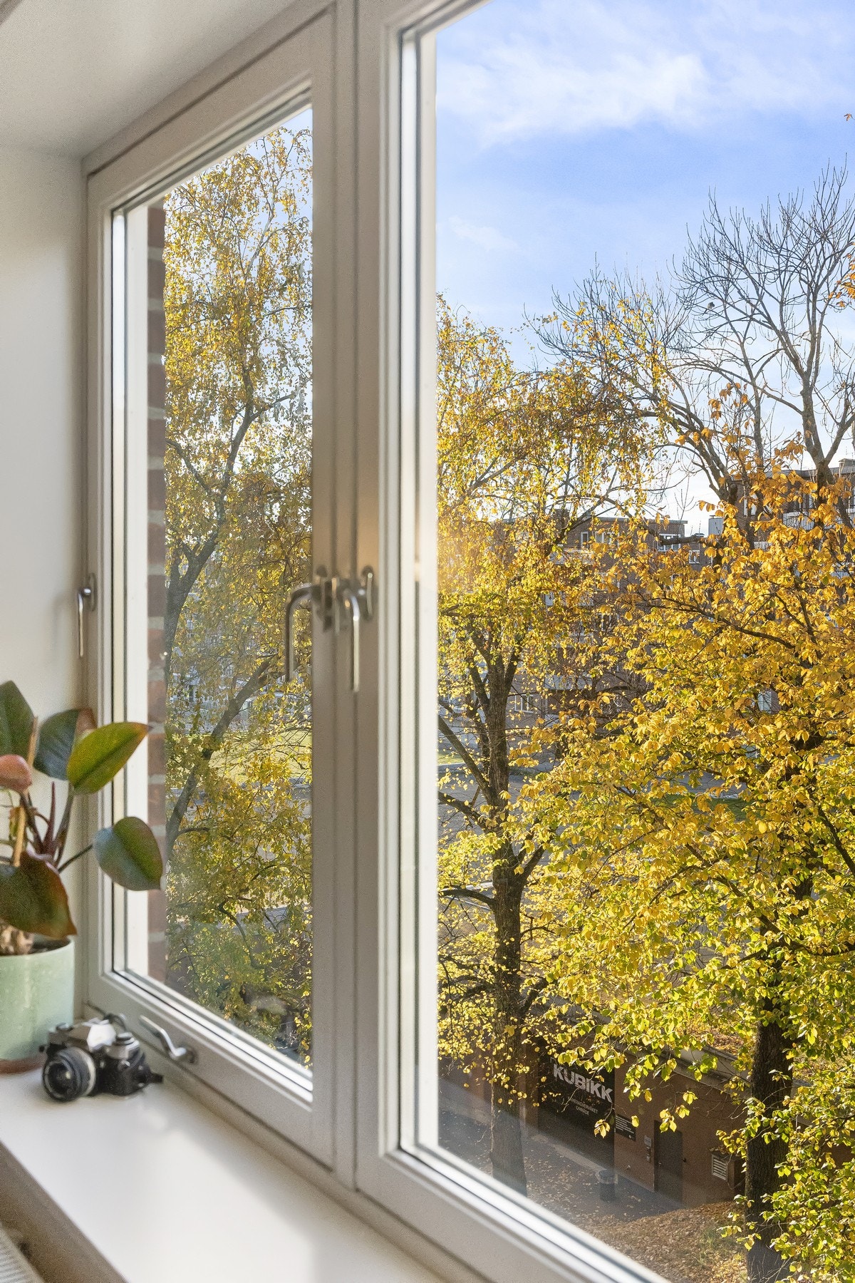 Utenfor vinduene danner grønne trær et vakkert og frodig utsyn, samtidig som boligens interne beliggenhet i bygget gir begrenset innsyn og en skjermet følelse. Galleribilde