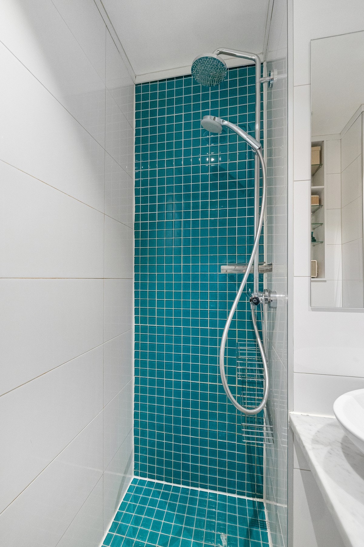 I dusjsonen er det dekorative mosaikkfliser i glass som gir et fint uttrykk. Dusjhjørnet har både regnfallsdusj og håndholdt dusjspyle. Galleribilde