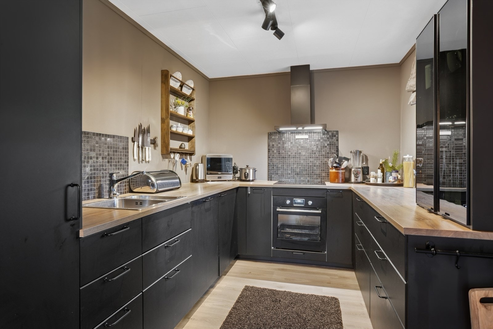 Kjøkkeninnredningen ble montert ny i 2020 og er moderne utført med mørke, glatte fronter, laminerte skrog, benkeplate av laminat og dobbel kjøkkenkum. Galleribilde