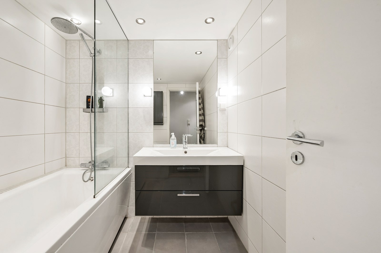 Kjeller har moderne bad med god belysning, varmekabler og god ventilasjon. Servant med speil og badekar med regnfallsdusj Galleribilde