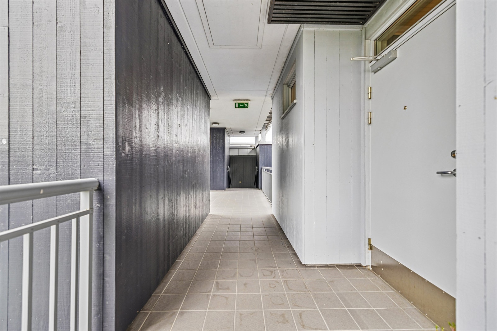 Adkomst til leiligheten via en overbygget og flislagt svalgang. Galleribilde