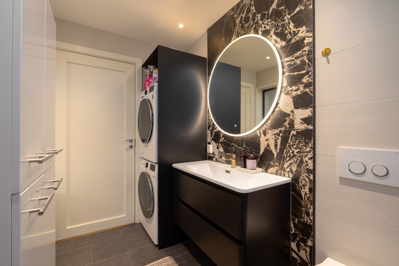 Elegant baderom med moderne servant og integrert vaskemaskin og tørketrommel. Galleribilde