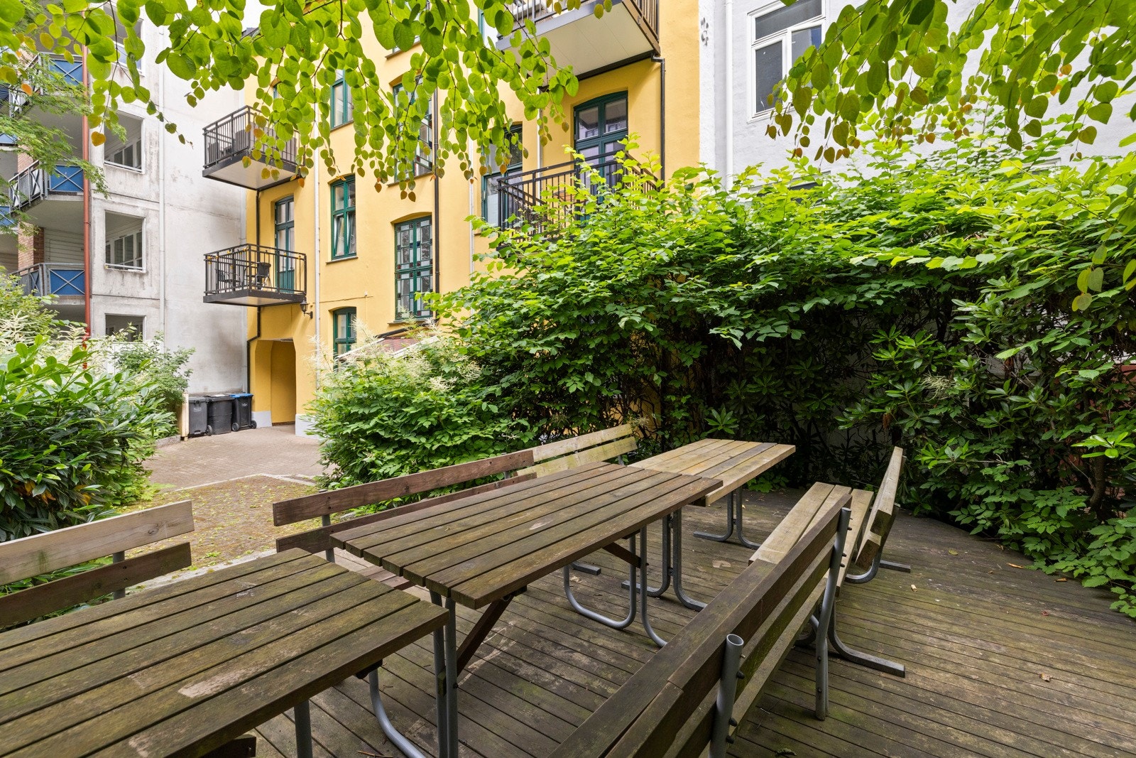 Hyggelige felles bakgård, et lunt og innbydende uterom til fri benyttelse for beboerne - et perfekt sted for både hverdagsavkobling og hyggelige nabomøter. Galleribilde