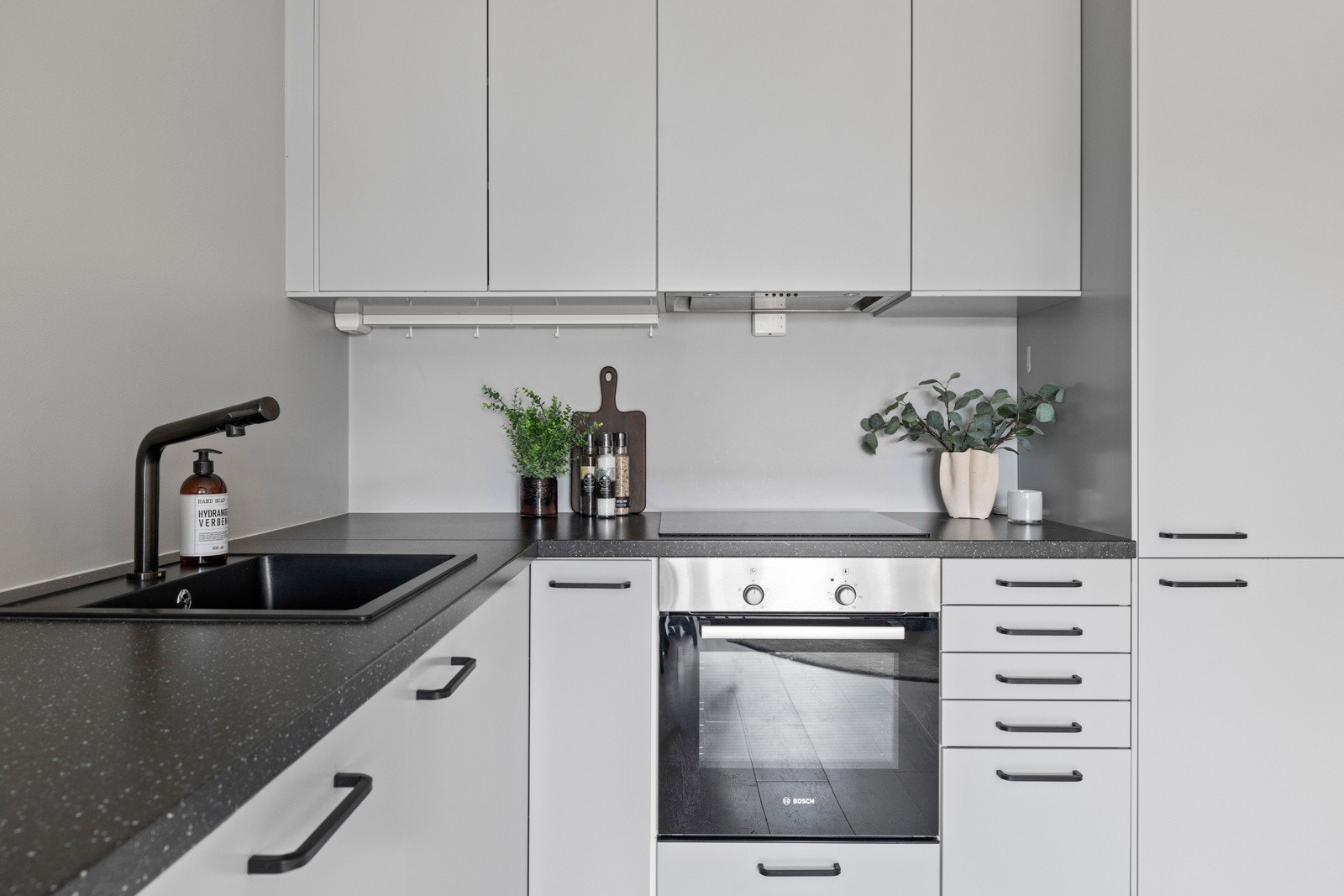 Glatt laminat kjøkkeninnredning, laminat benkeplate, kullfilter vifte, nedfelt kum, integrert komfyr, platetopp og oppvaskmaskin. Galleribilde