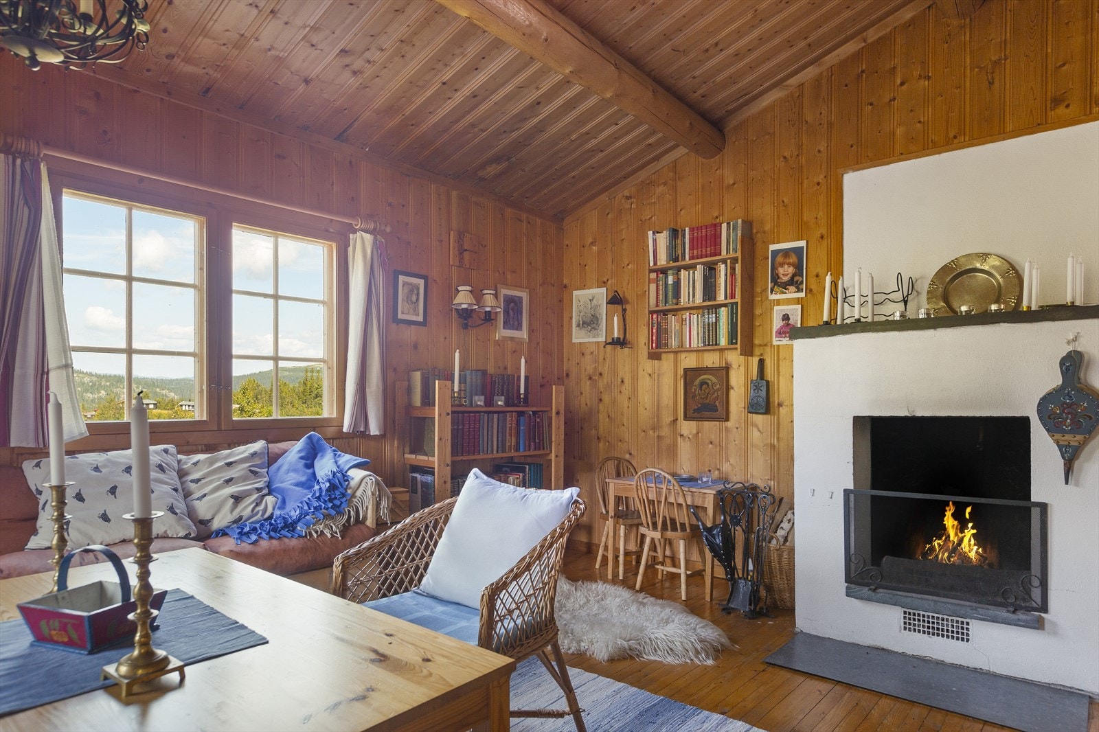 I stua er det både sofahjørne og spisebord med benk og stoler, og fra begge sittegruppene kan en nyte synet av flammene i en åpen, hvitmalt peis. Galleribilde