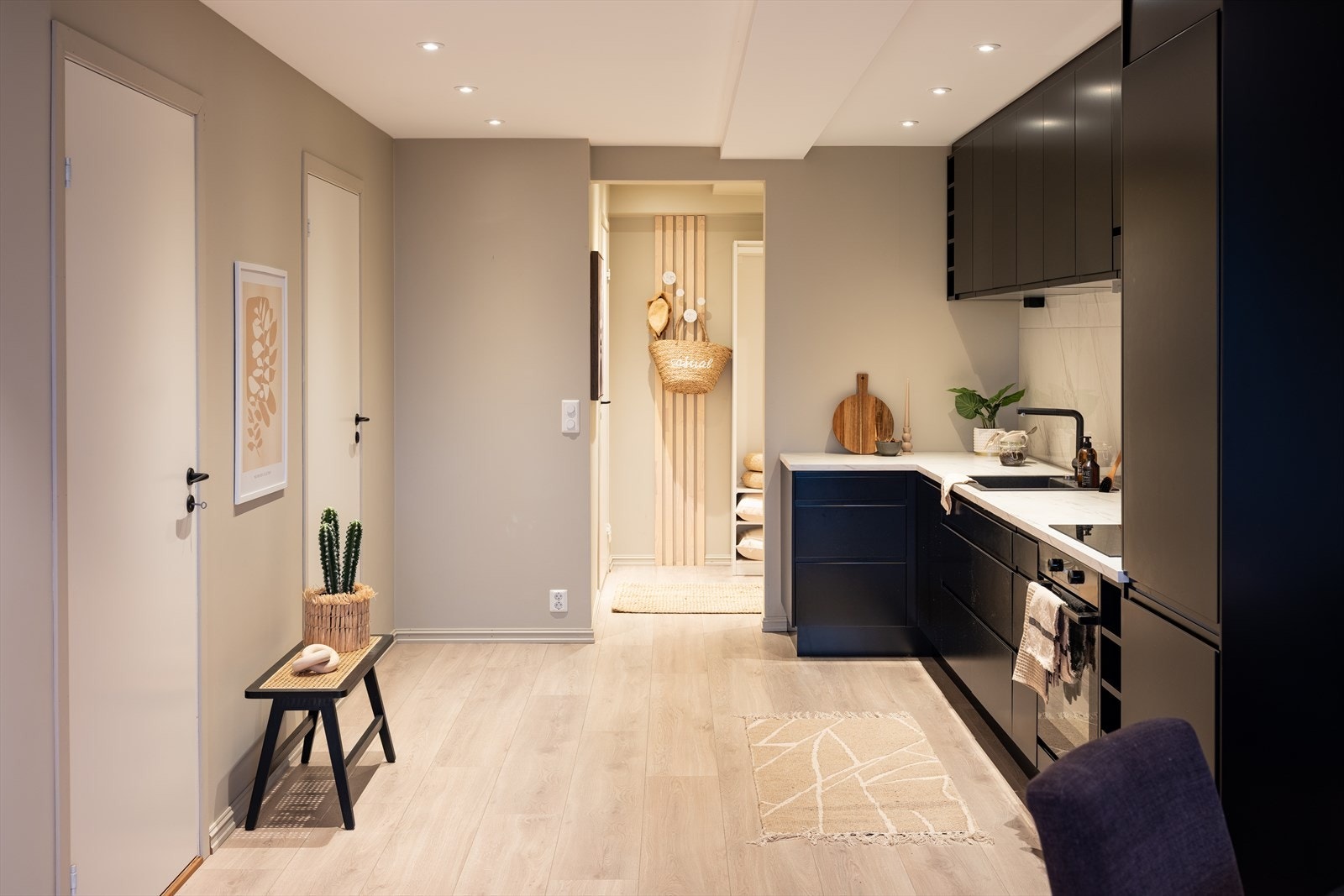 Kjøkkenet har et moderne uttrykk med grepsfrie skap og skuffer i stilren, sort utførelse. Galleribilde