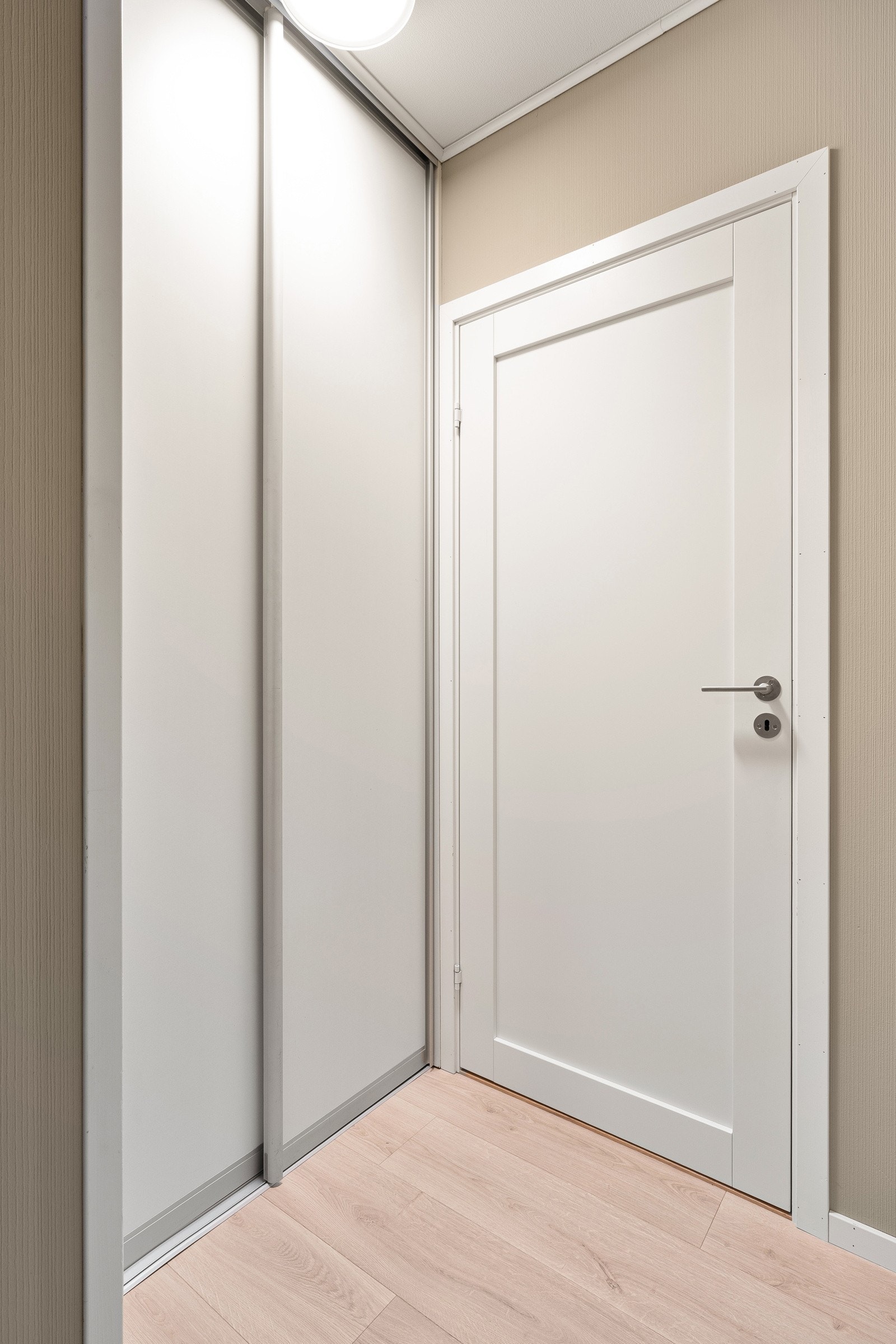 Liten mellomgang ved bad hvor det er etablert praktisk skyvedørsgarderobe.