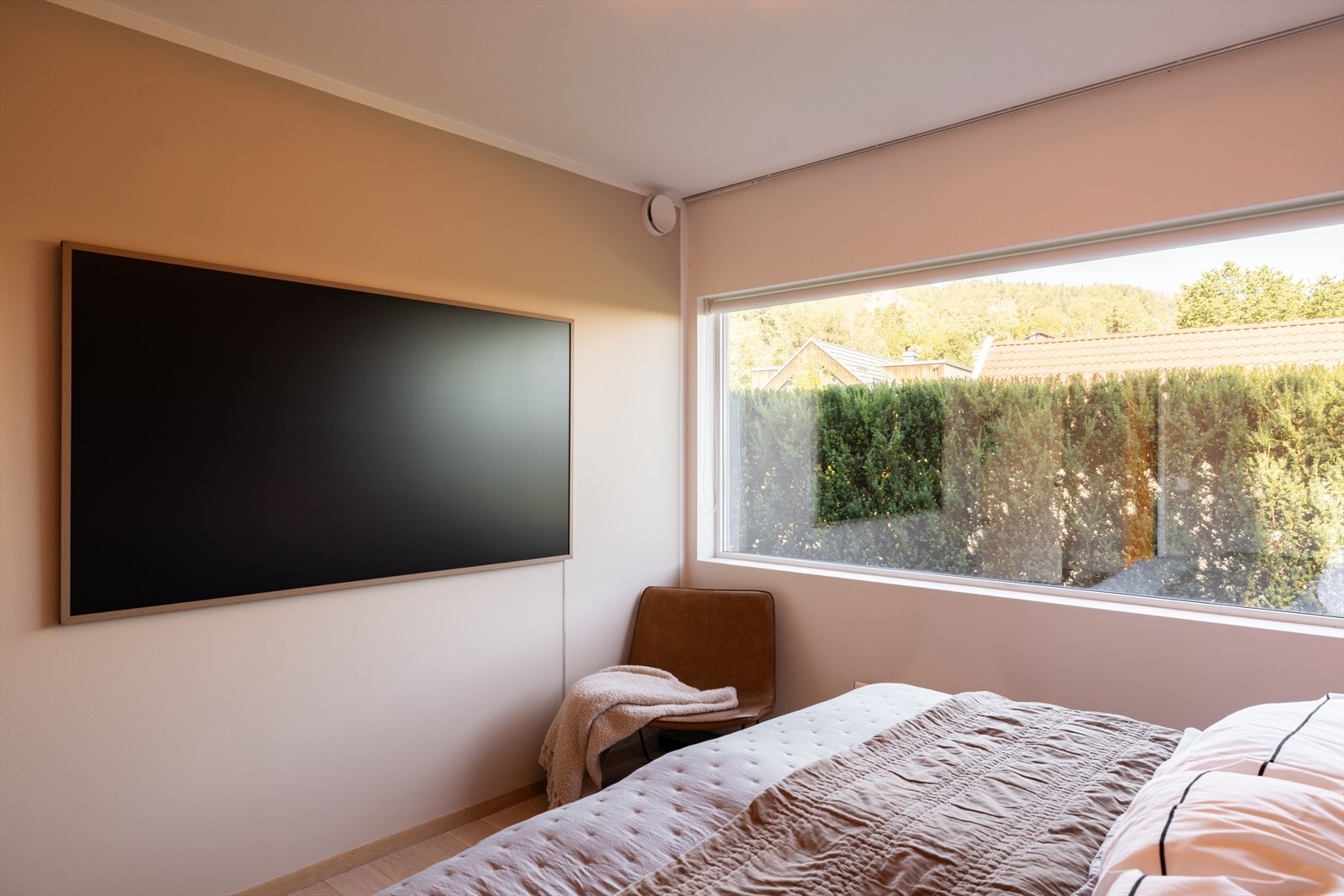 Rommet har vinduer langs endeveggen, tekstiltrukne paneler opp til taket på veggen over sengeplassen og tv-uttak på motsatt vegg. Galleribilde