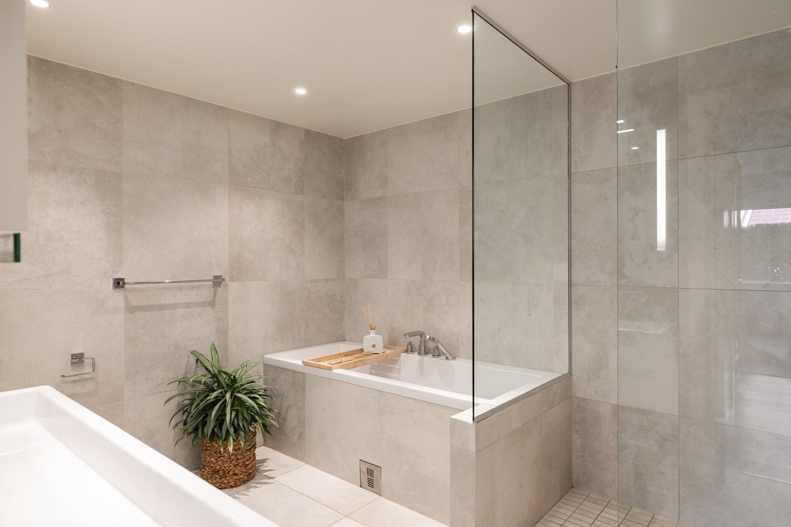 Badet er utført med lysegrå fliser på gulv og vegger, gulvvarme og downlights. Galleribilde