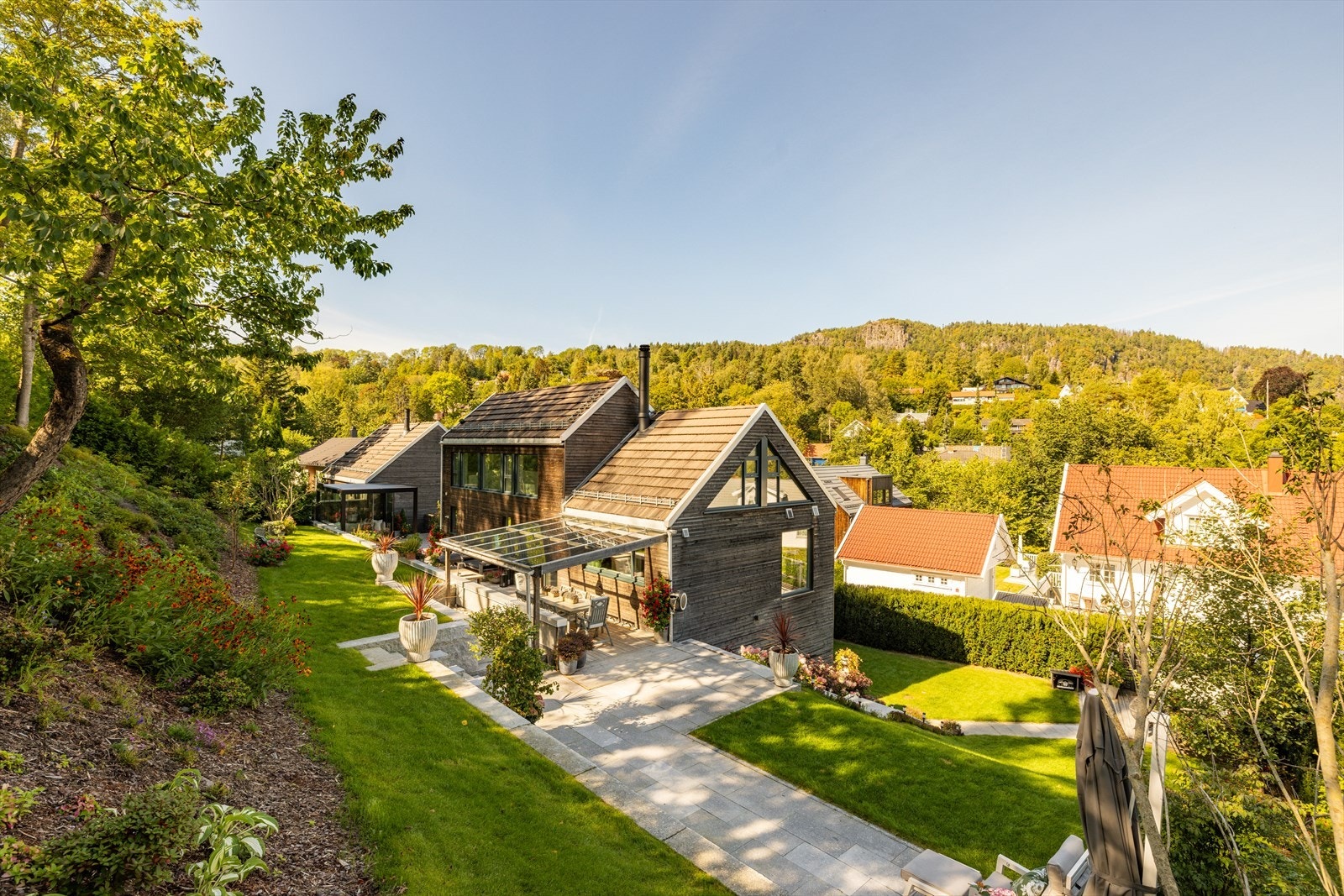 Gjennomførte uteområder med steinlagte soner, innglasset pergola og parkmessig beplantning - designet for å oppleves dobbelt så stort. Galleribilde