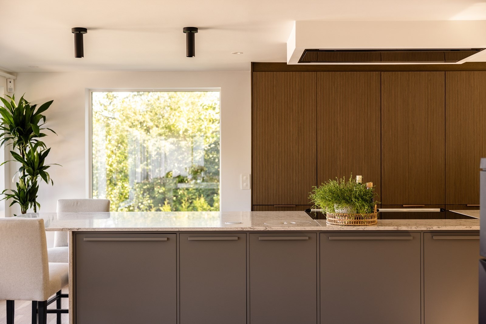 Kjøkkenøy midt i rommet gir god arbeidsflyt, oppbevaring og plass til noen å sitte, med elegante grå fronter og marmorert stein. Galleribilde