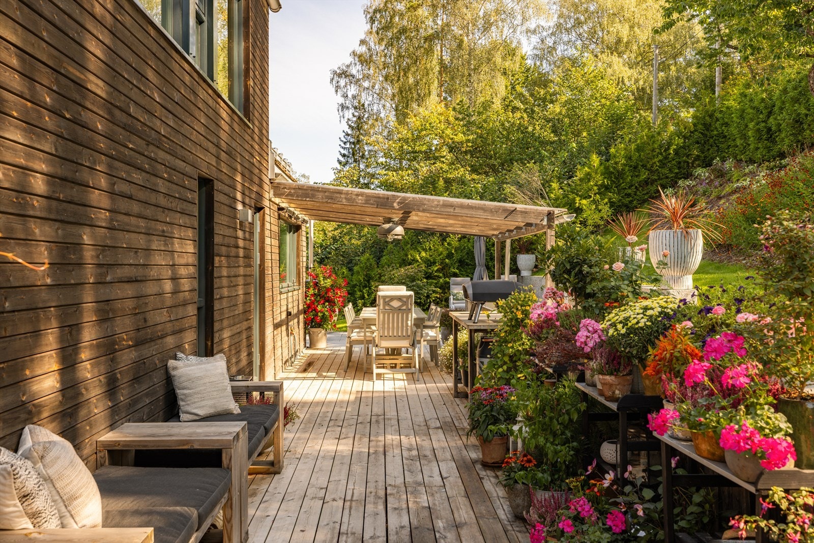 Et rekkverk i tre strekker seg langs sydsiden av disse to terrassene og skaper blant annet et skille mot en nyere terrasse fra 2024, med dekke av steinfliser. Galleribilde