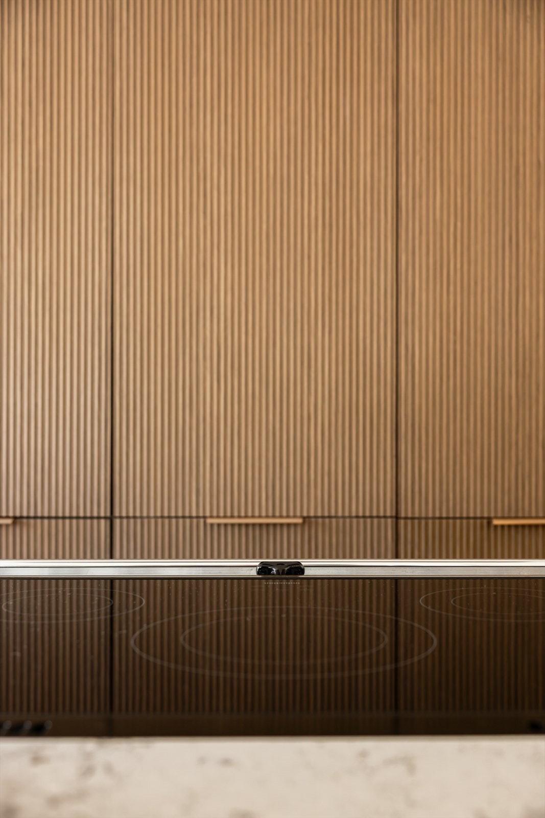 Høyskapene og benkeskapene har mørkebrune rillefronter i trestruktur med bronsefargede metallhåndtak Galleribilde