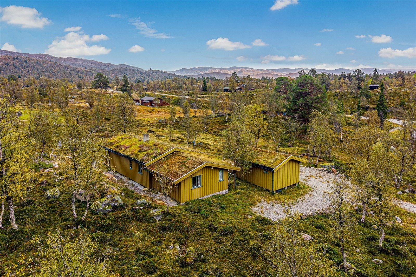 Hytta fremstår lavmælt der den ligger i skråningen med adkomst nedenfra. Galleribilde