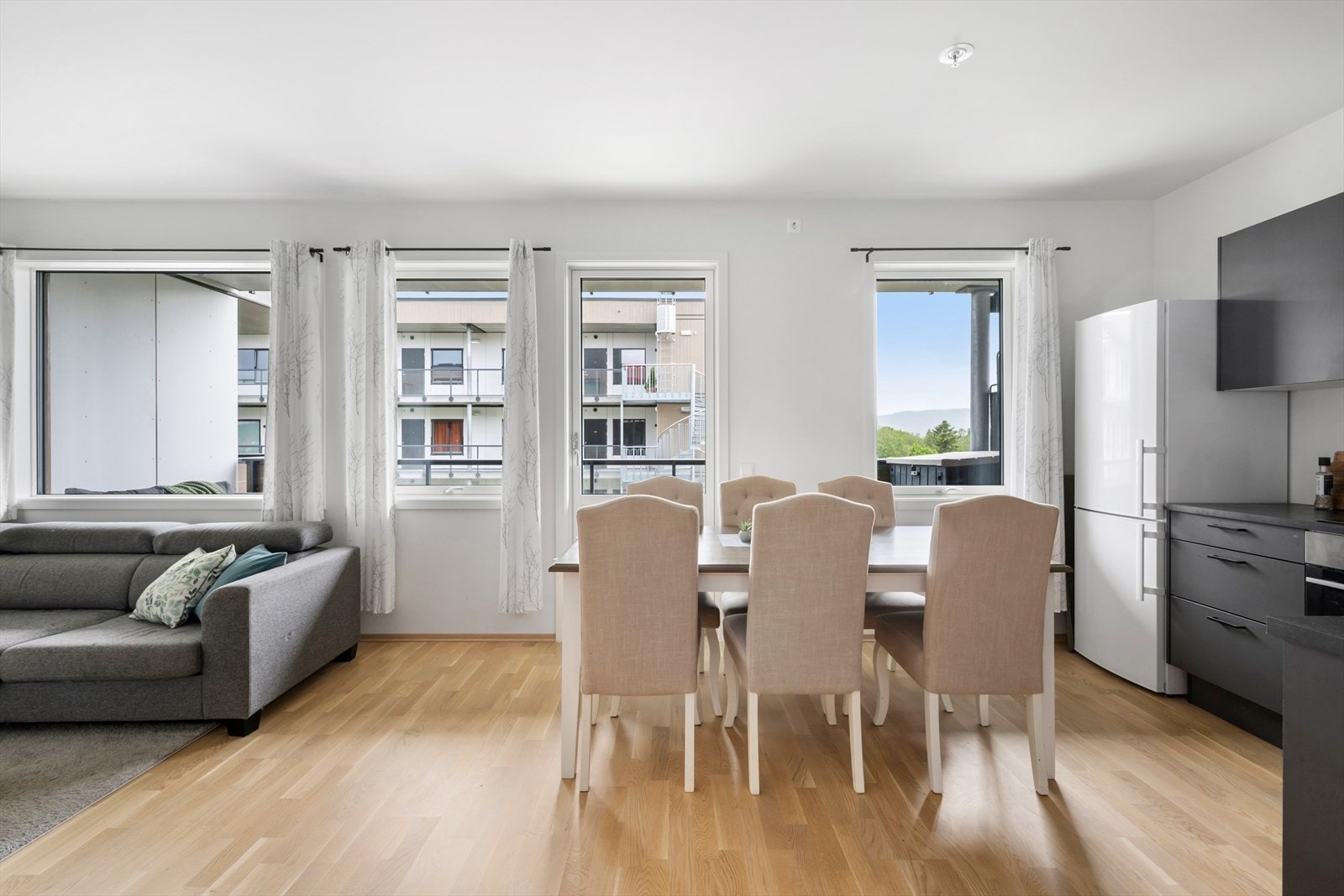 Åpen kjøkken- og spiseplassløsning. Store vindusflater gir rikelig med naturlig lys, og rommet fremstår som både romslig og funksjonelt med stilrent interiør og god planløsning. Galleribilde