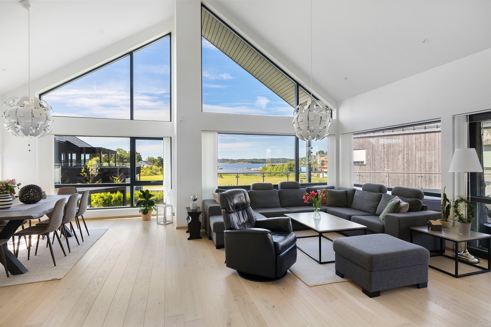 Den åpne stueløsningen kombinerer god takhøyde med store vinduer som slipper inn rikelig med lys og gir vakker utsikt til sjøen Galleribilde