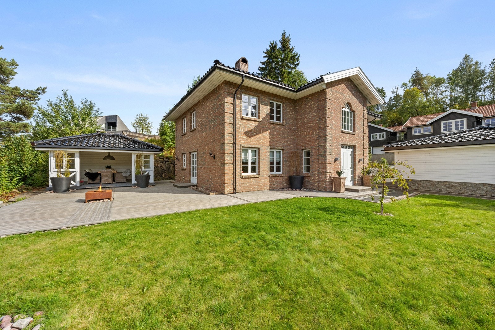 Flatt hageareal med stedvis beplantning og flaggstang. Galleribilde