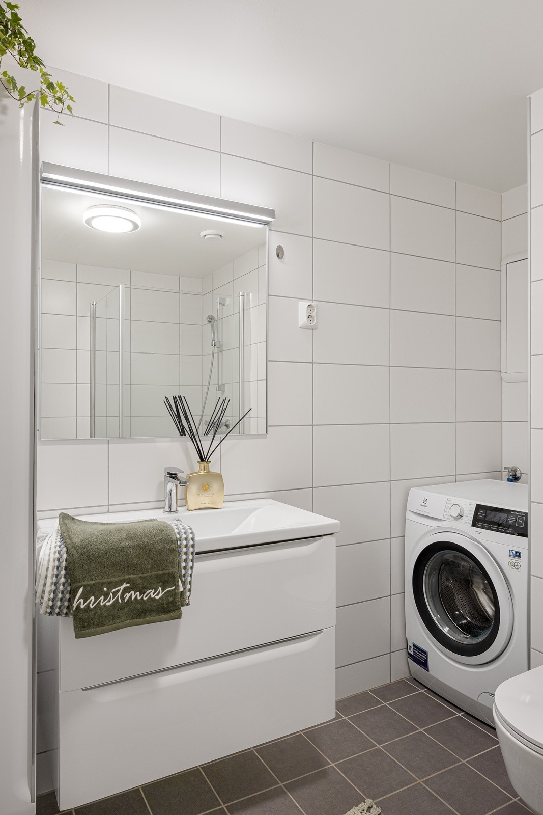 Baderomsinnredningen har hvite, glatte fronter og består av en heldekkende servant på en skuffeseksjon, et høyskap og et stort speil med belysning Galleribilde